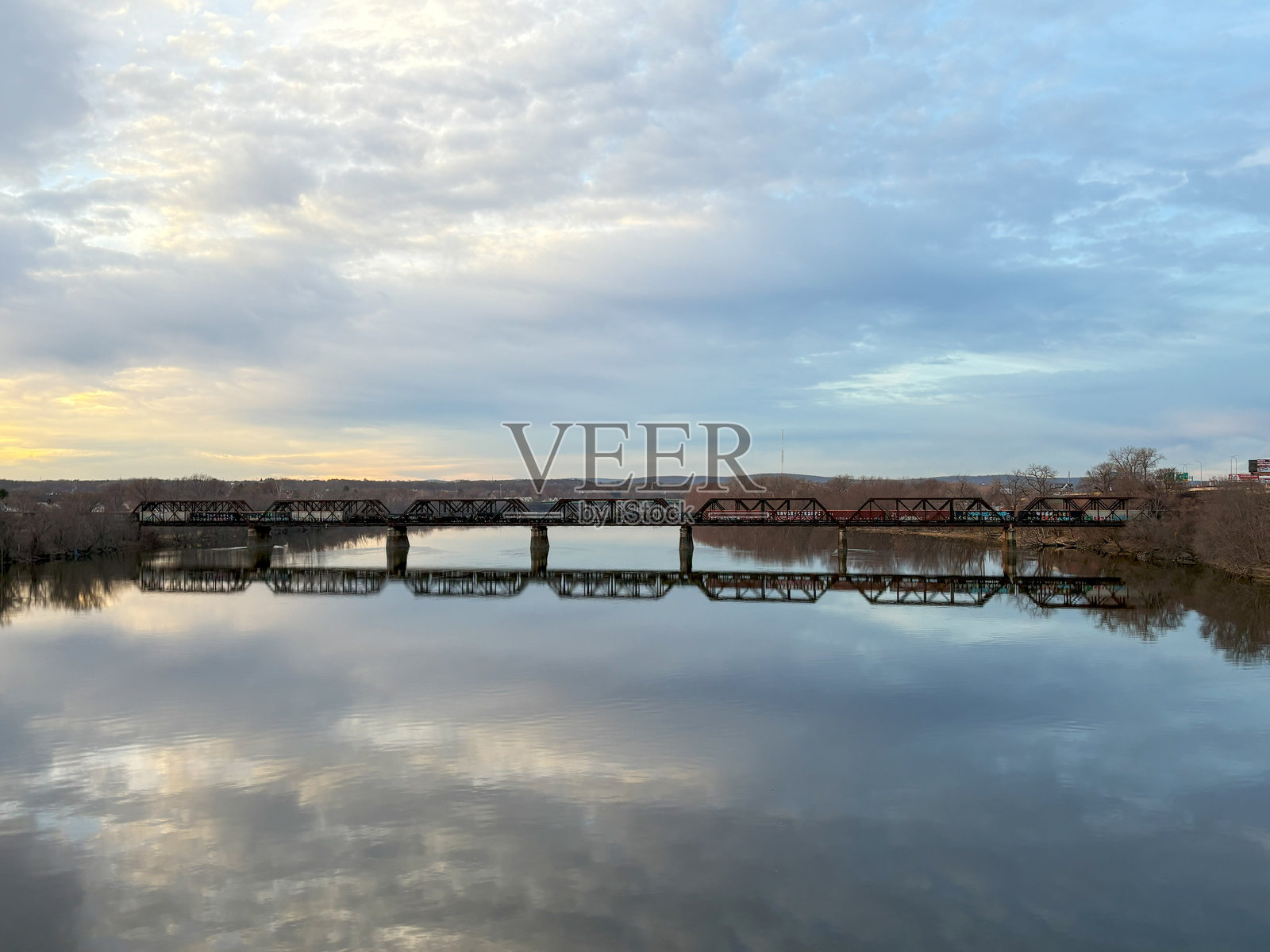 日落时分，桥梁倒映在宁静的河边水面上照片摄影图片