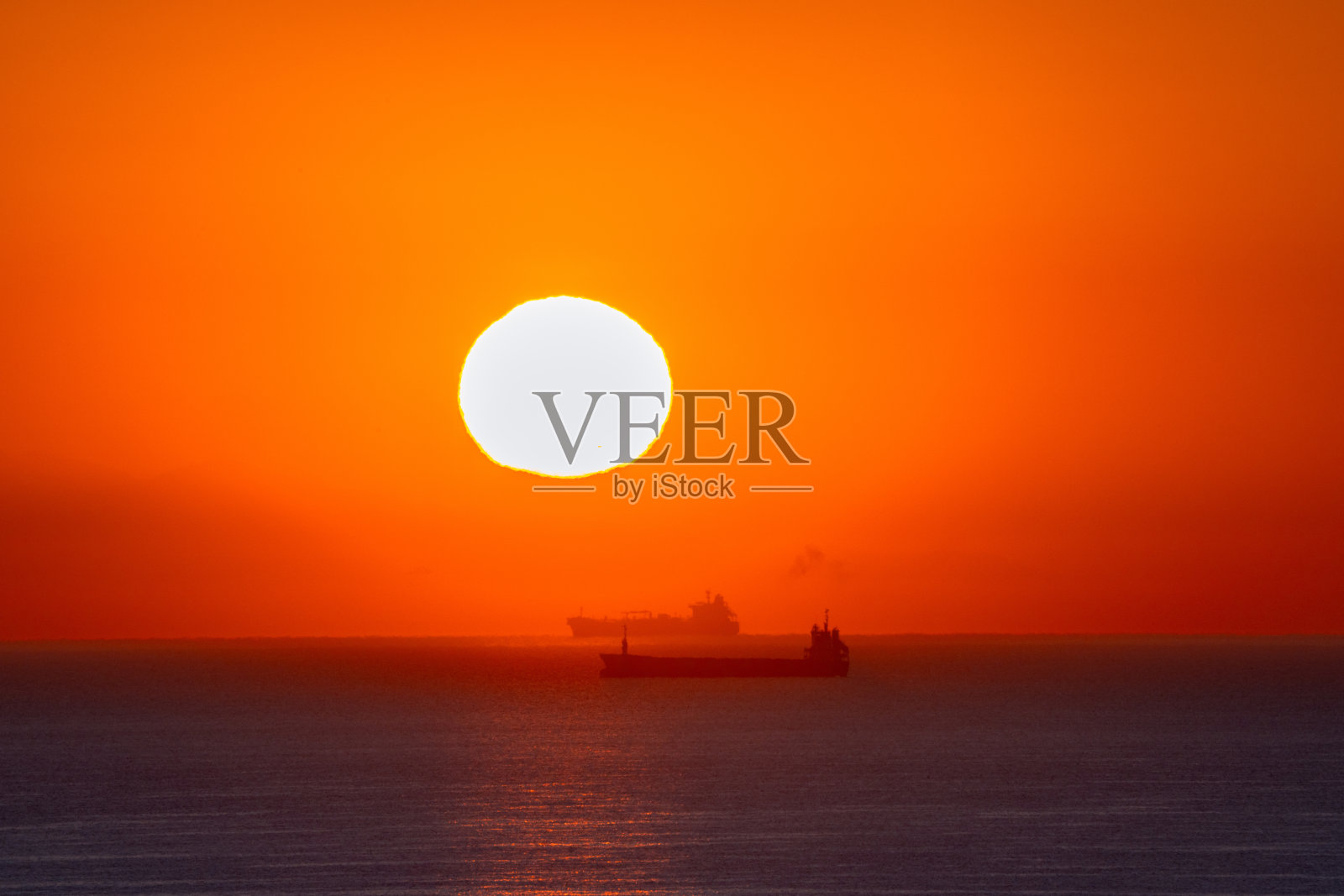 日落和日出时，地平线上货船的剪影照片摄影图片