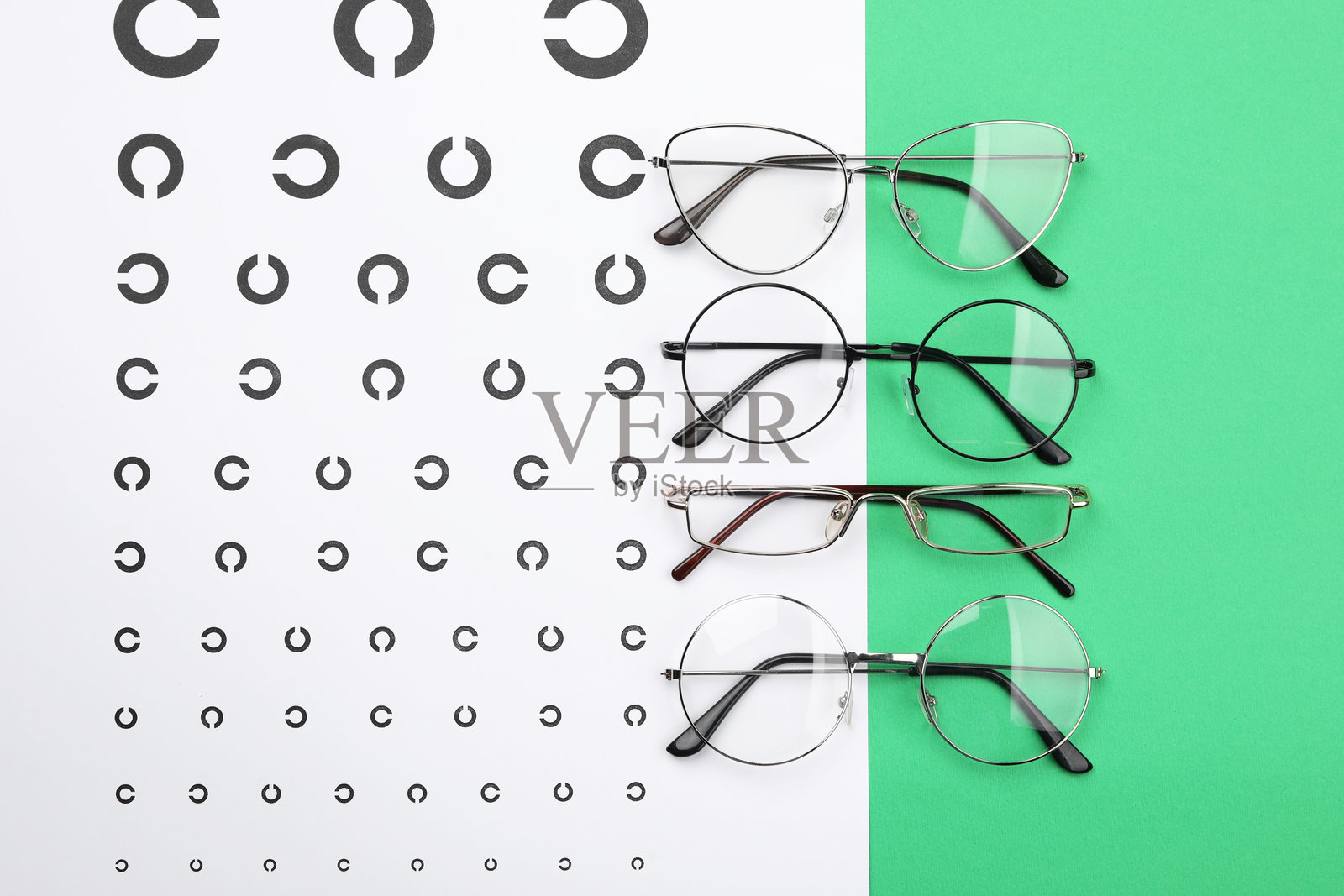 绿色背景上的视力测试表和眼镜，平铺展示照片摄影图片