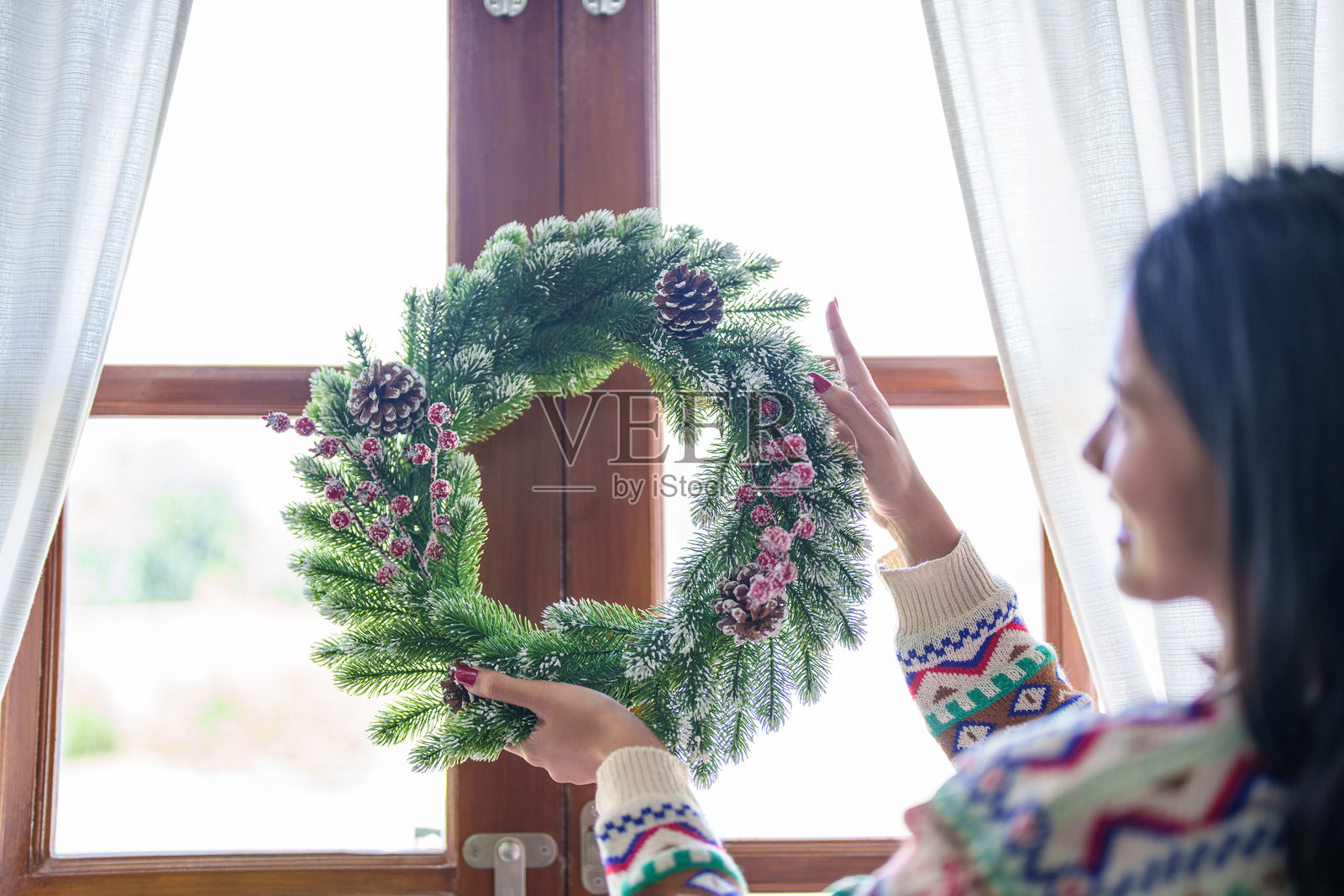 女人用手工制作冬季绿植装饰的槲寄生花环，正在制作美丽的圣诞花环。照片摄影图片