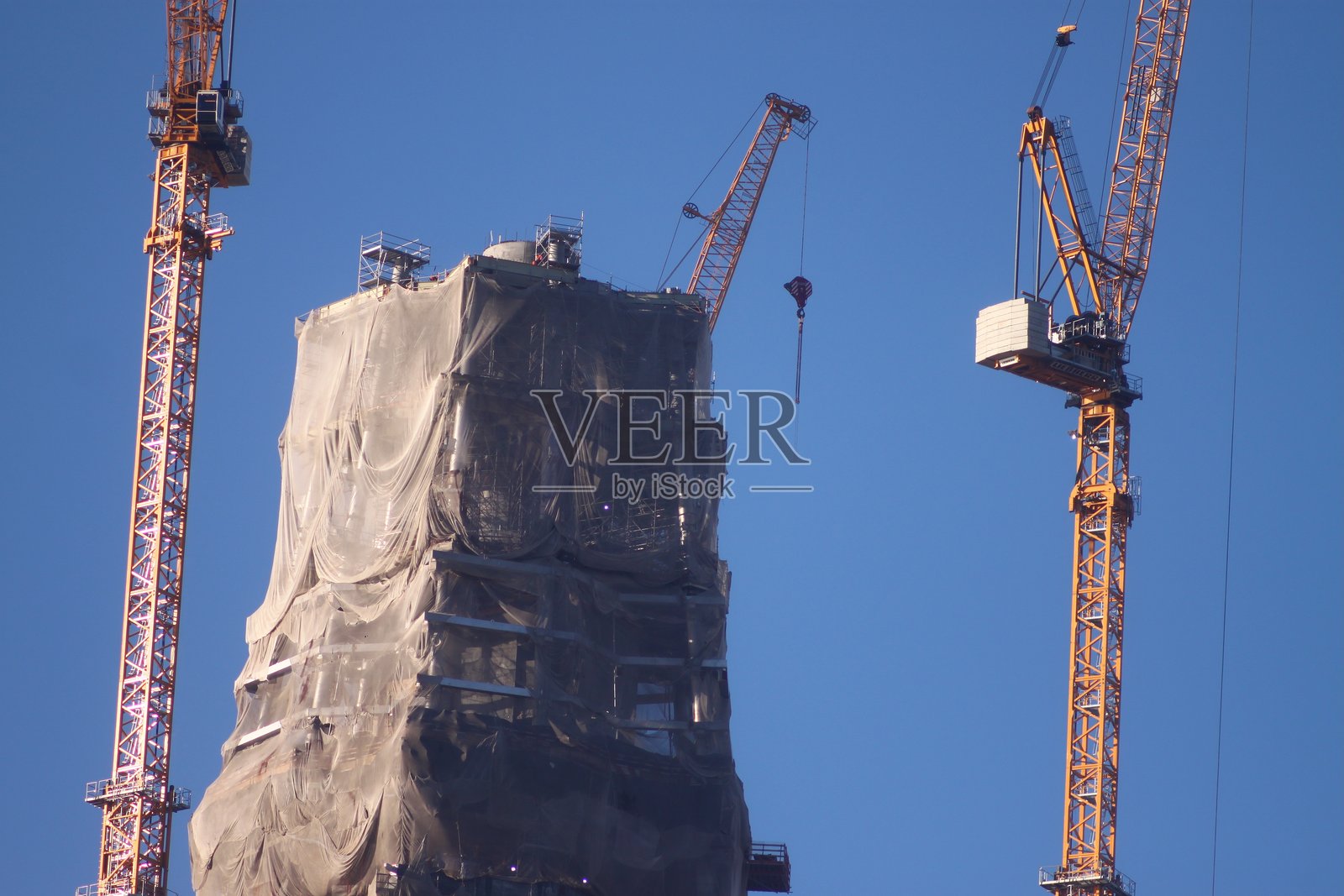 一座大型建筑正在施工，背景中有起重机。照片摄影图片