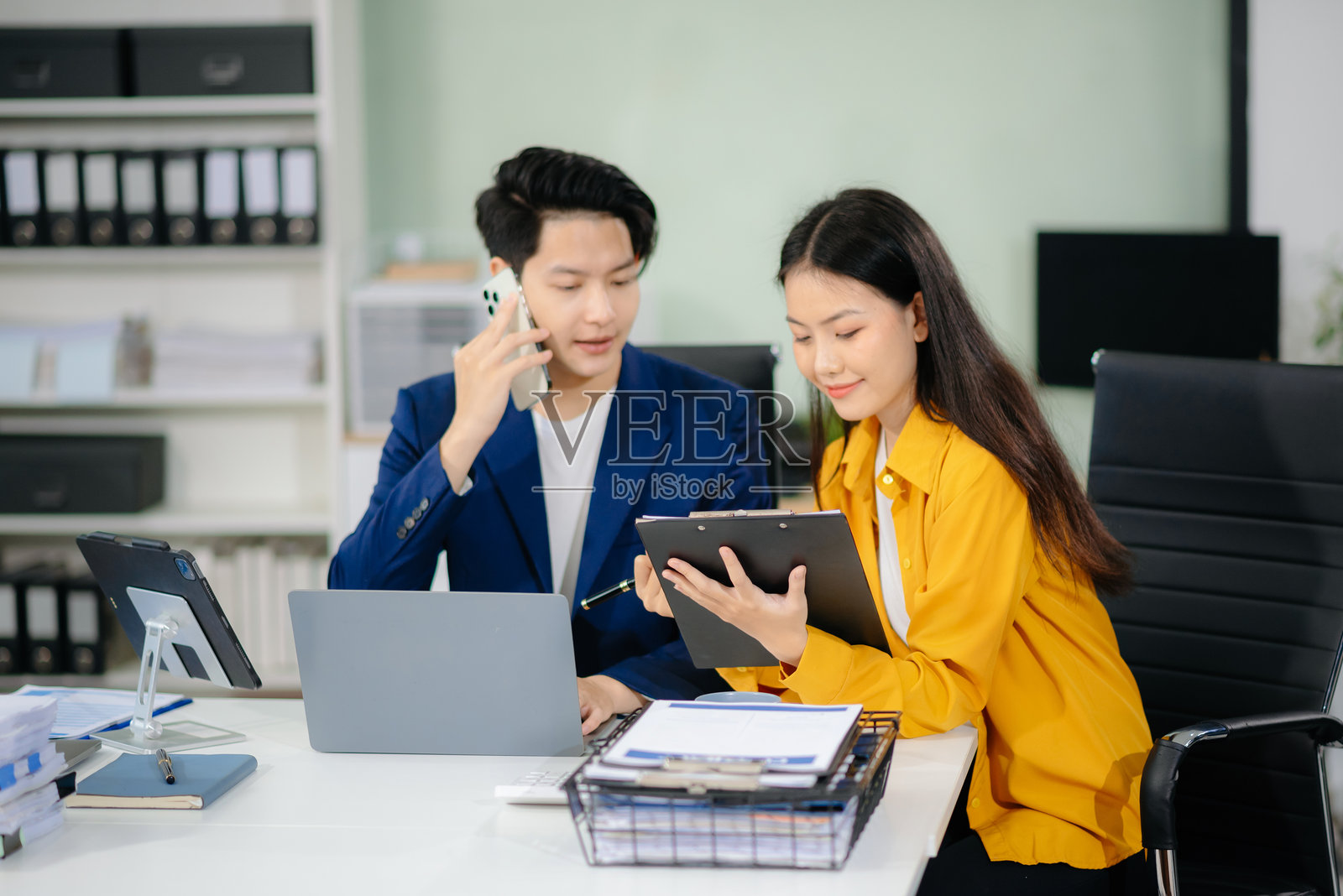 两名商务人士在使用智能手机和笔记本电脑交谈照片摄影图片