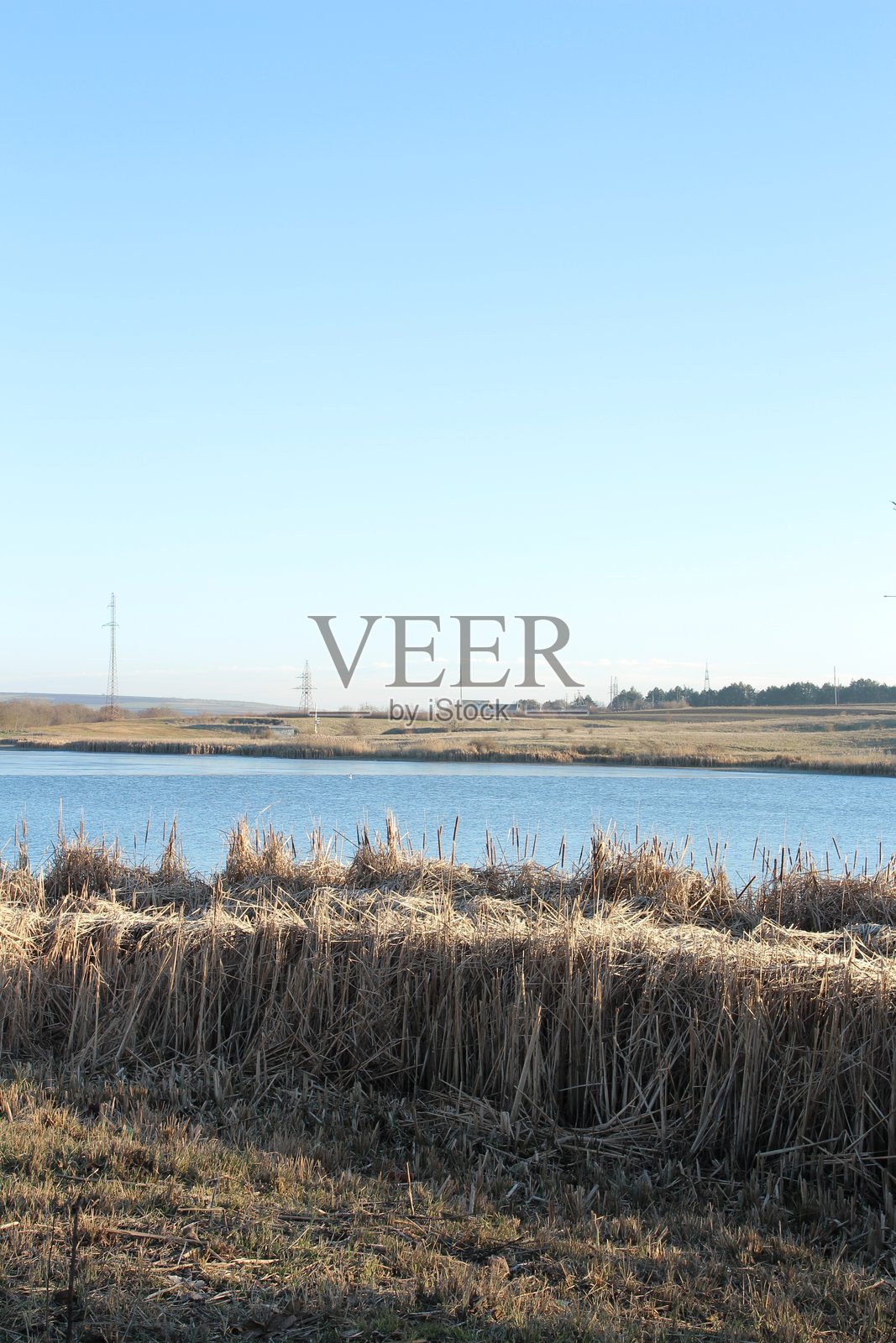 一片水域，远处有草地和一座风车照片摄影图片