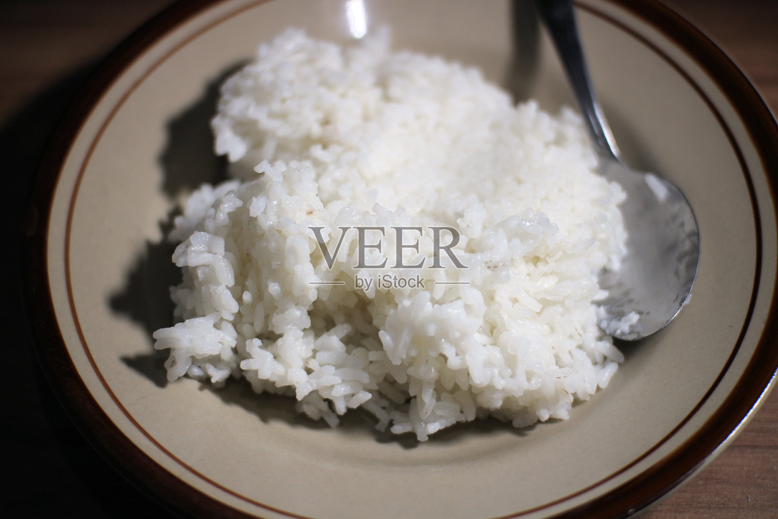 盘子里的蒸白米饭和勺子照片摄影图片