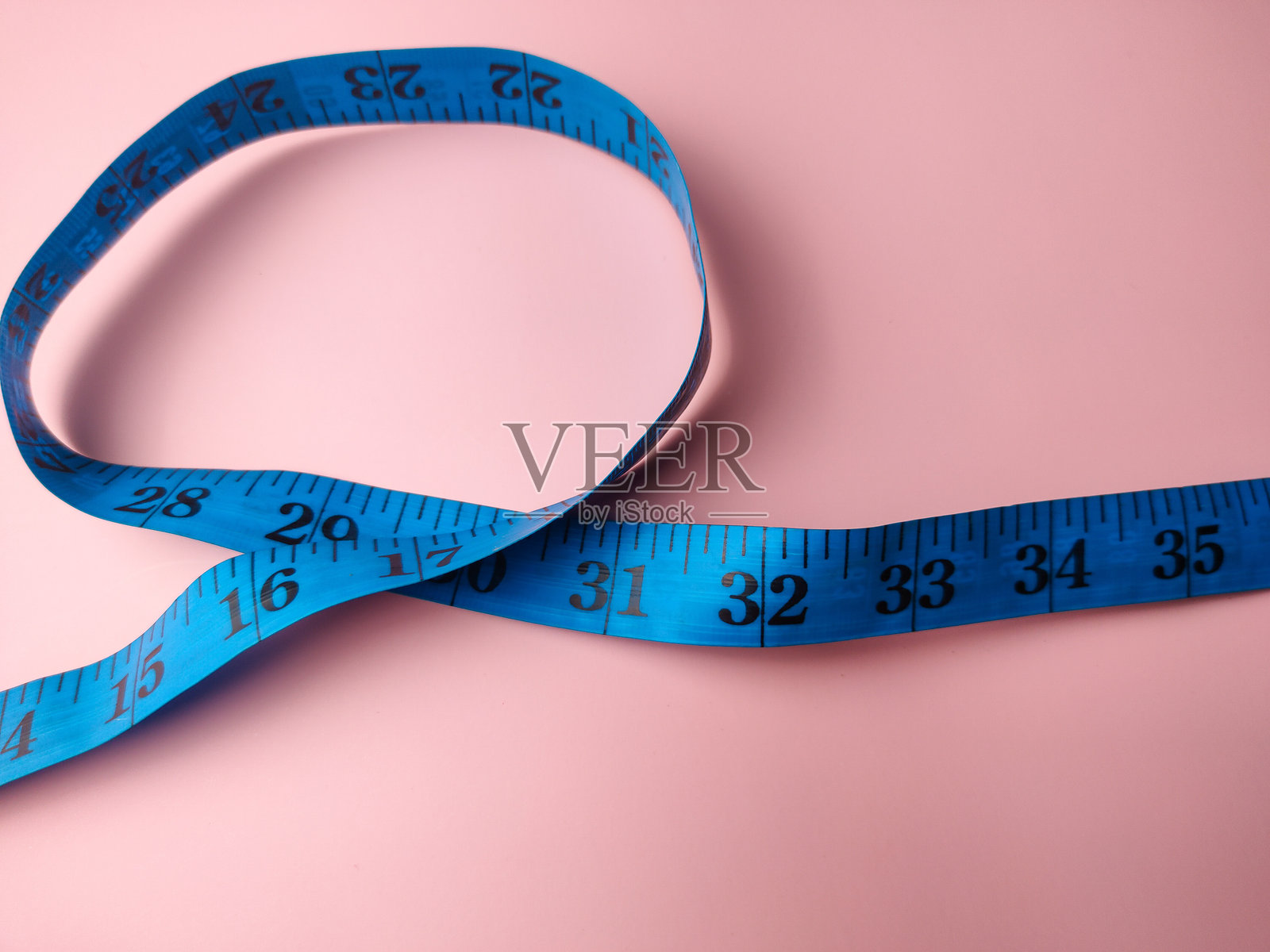 粉色背景上的蓝色卷尺特写。医疗与健康概念照片摄影图片