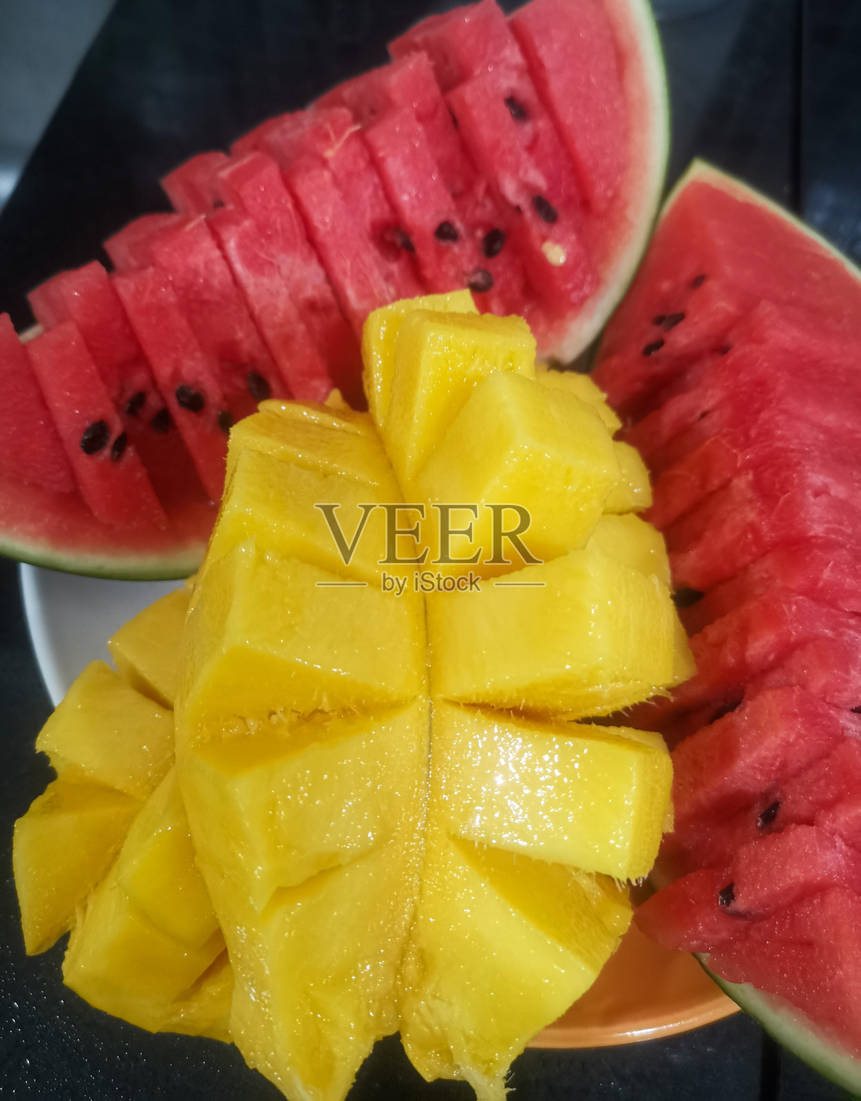 盘子里放着一片西瓜和一片芒果照片摄影图片