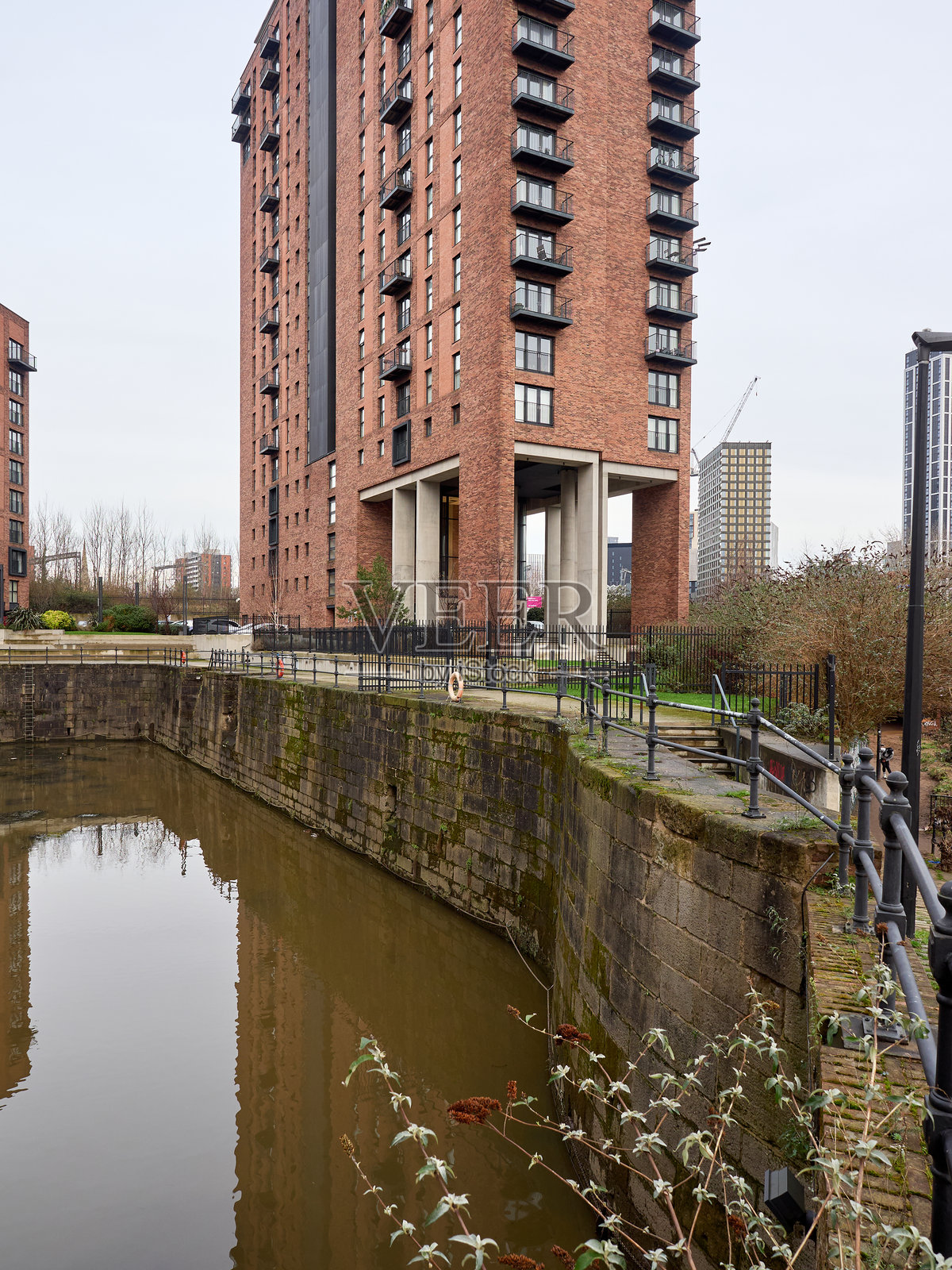 高耸的砖砌公寓楼倒映在宁静的城市水道中。照片摄影图片