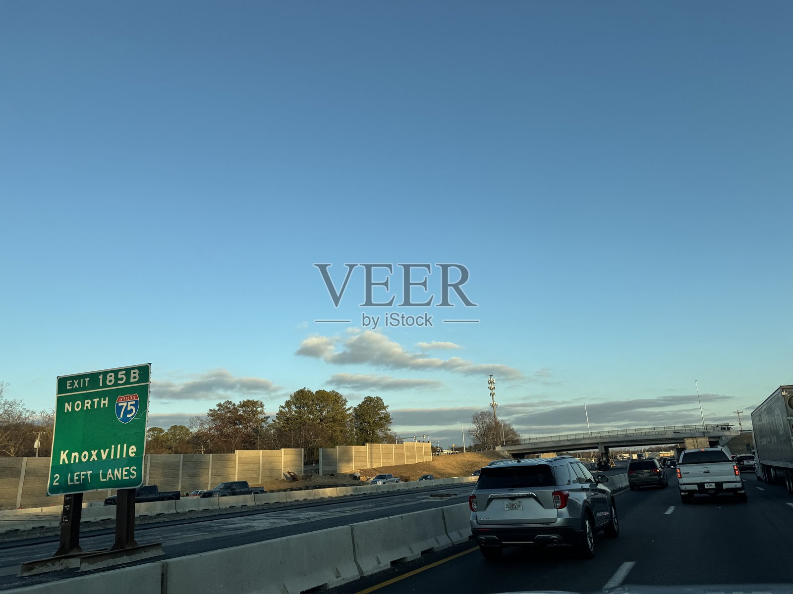车辆在州际公路上行驶，背景是指向诺克斯维尔的出口标志和晴朗的蓝天。照片摄影图片
