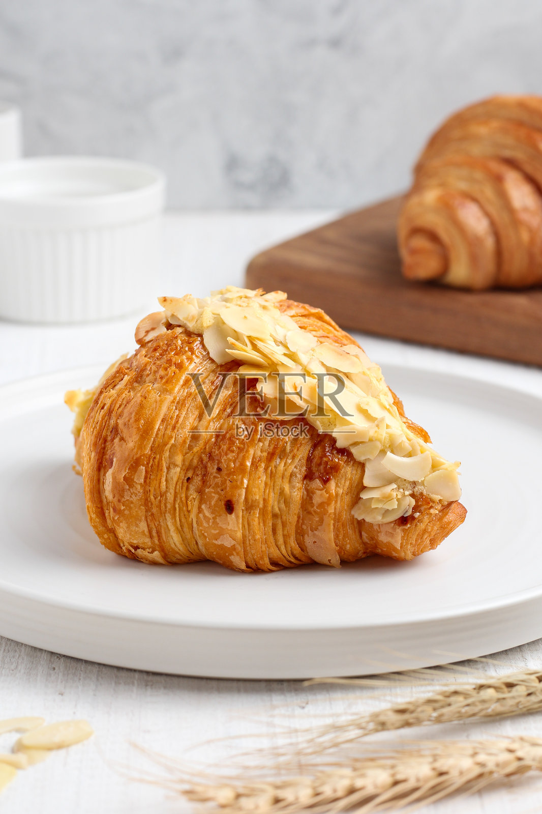 白盘上的杏仁可颂 pastry。照片摄影图片