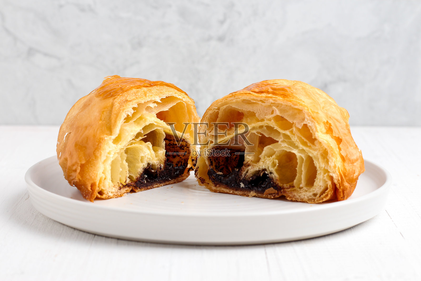 白盘上的可颂 pastry。照片摄影图片