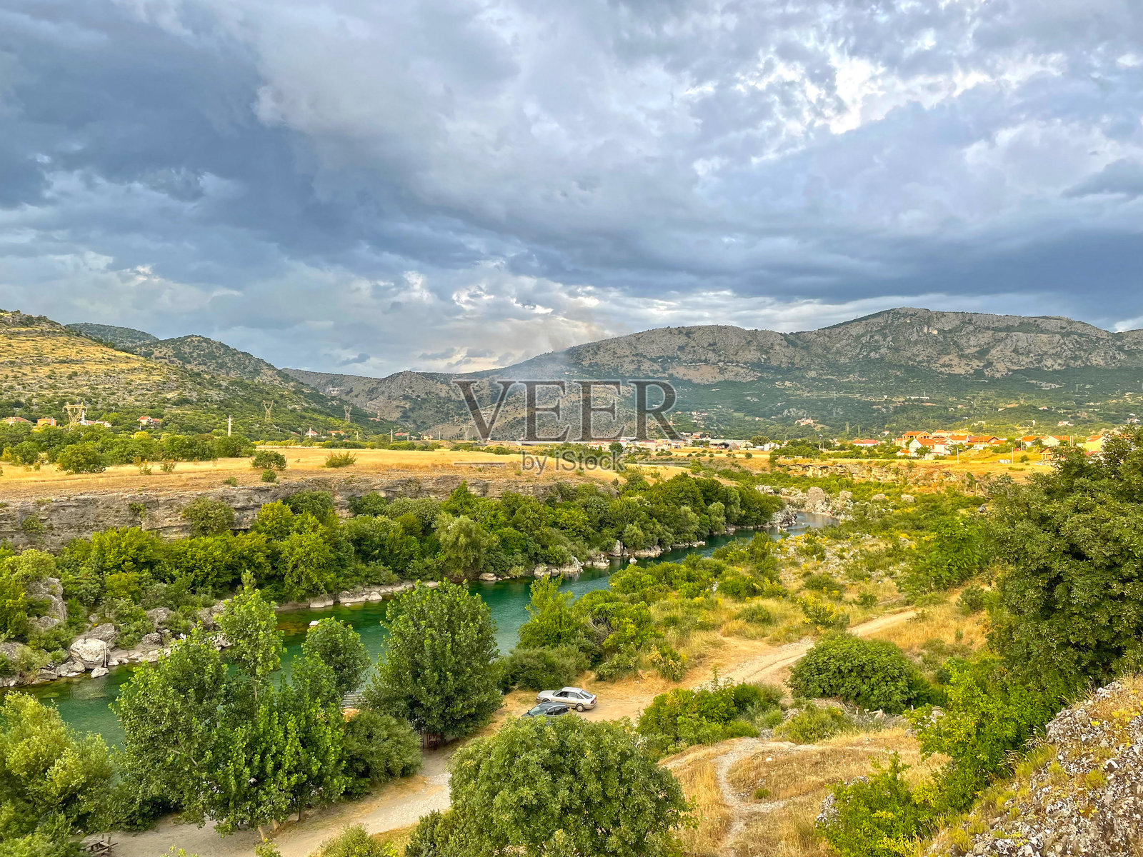 阴云密布的夏季河岸，绿草如茵的平原和山丘照片摄影图片