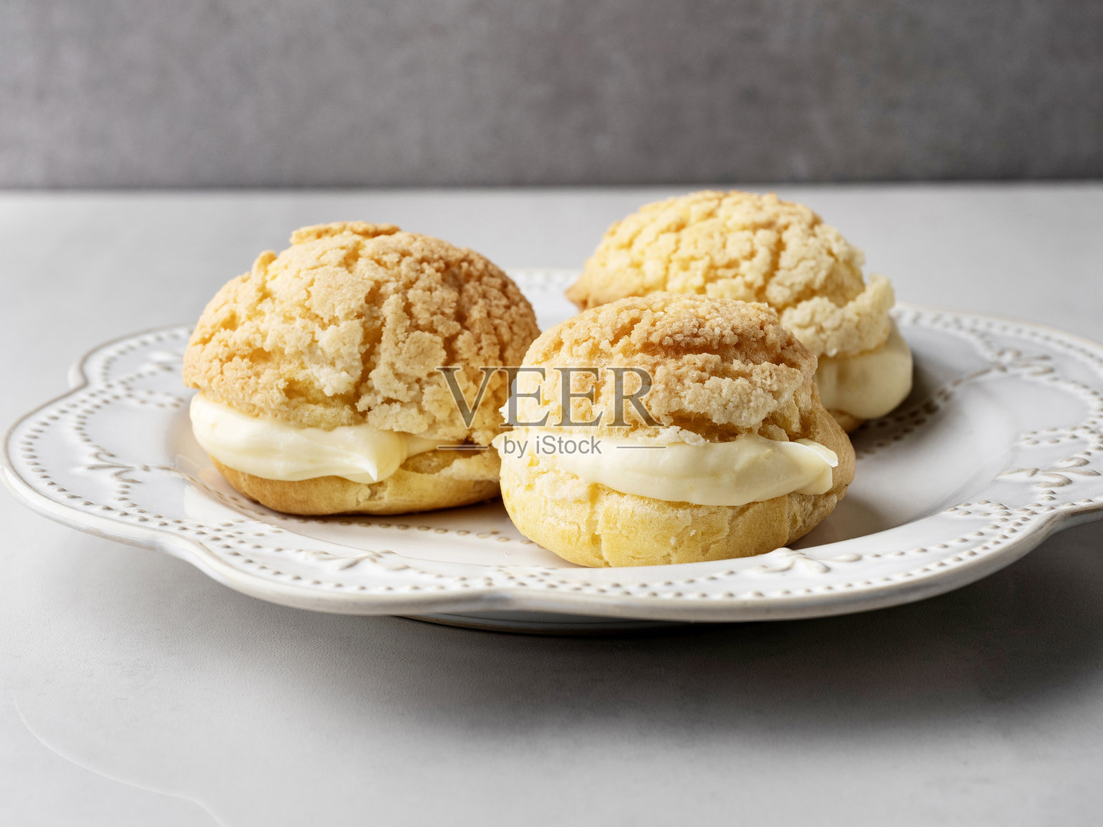 灰色背景上的泡芙饼干，内填打发奶油。泡芙。自制奶油泡芙。泡芙。闪电泡。照片摄影图片