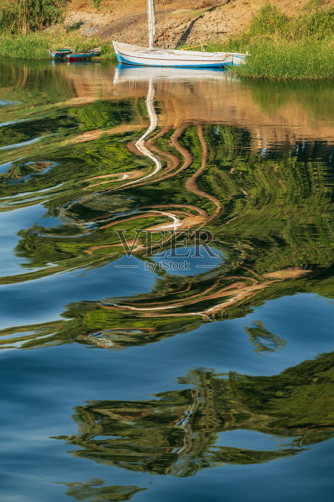 尼罗河上的帆船，水面因经过的游船而泛起涟漪照片摄影图片