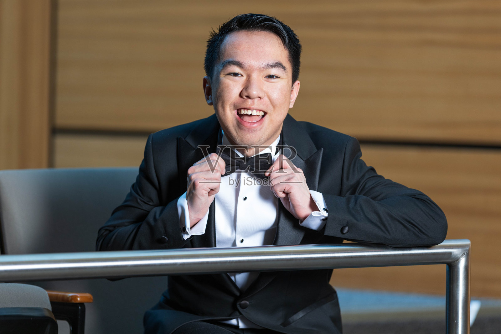 年轻男子坐着调整他的领结照片摄影图片