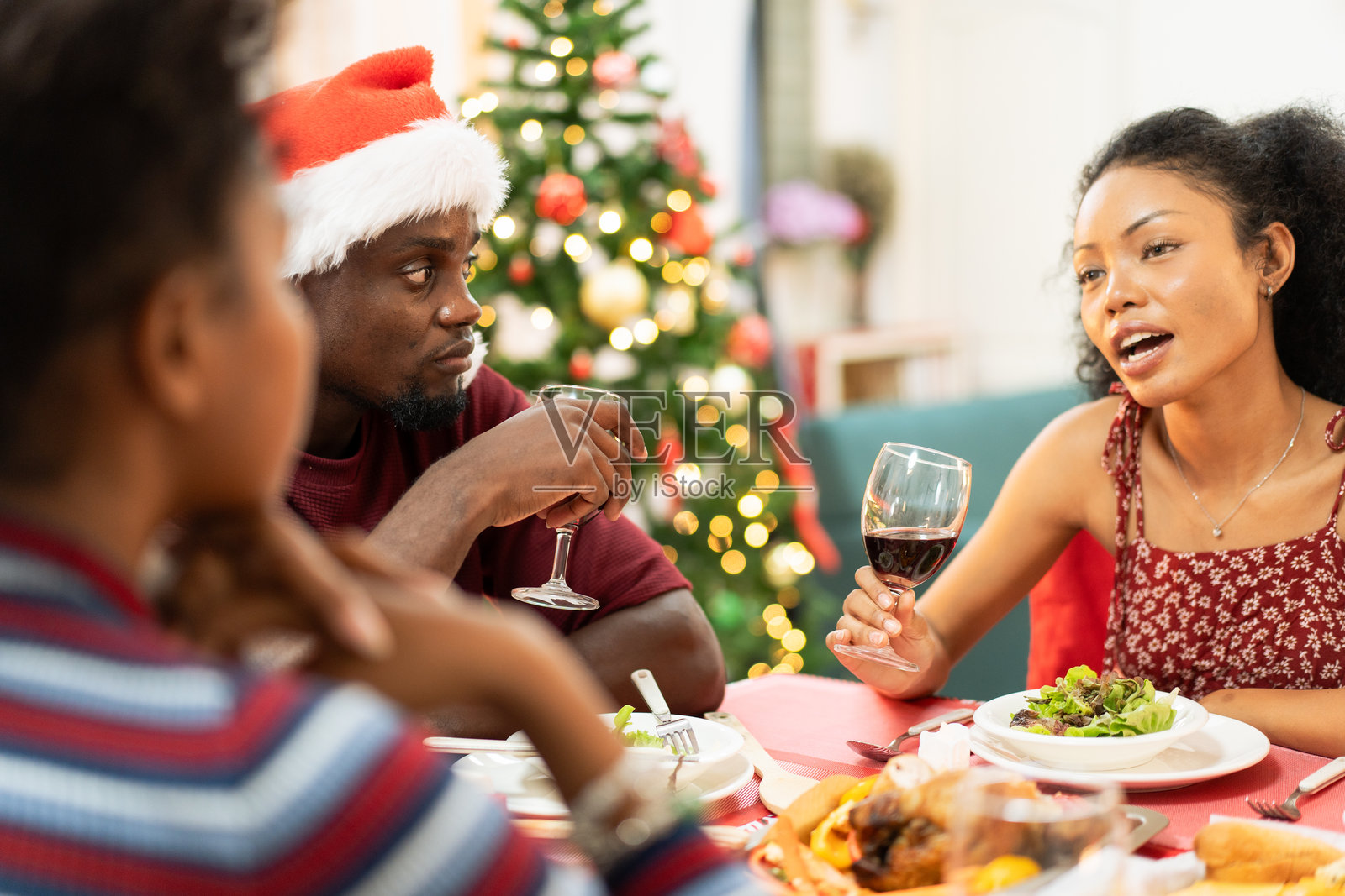 非洲家庭在家中共进圣诞晚餐。人们在餐桌上喝酒、吃饭，享受交谈的乐趣。节日庆祝派对，假期里有美味的盛宴。照片摄影图片