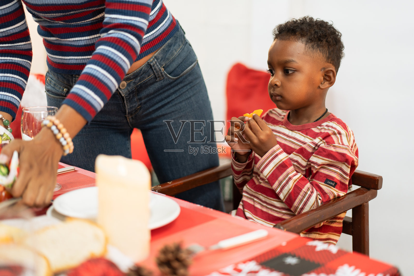 快乐的非洲男孩在家中庆祝圣诞节的节日晚餐时坐在餐桌旁照片摄影图片