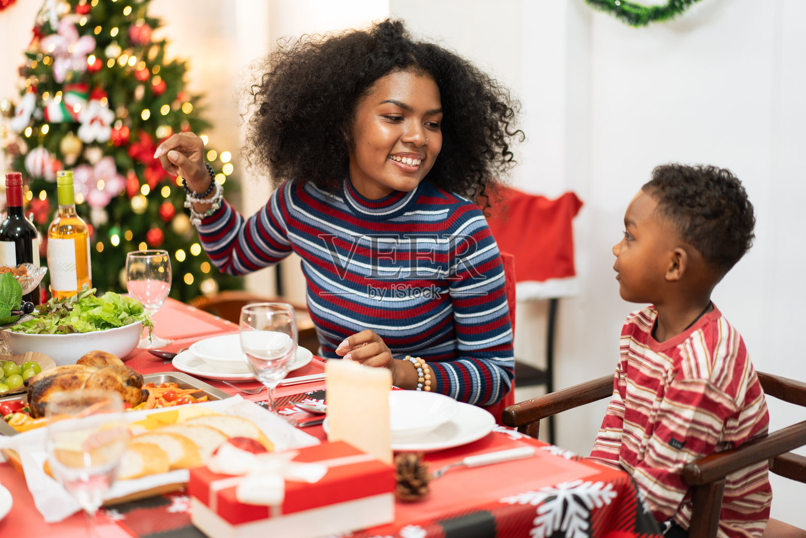 非洲家庭在家中共进圣诞晚餐。人们在餐桌上喝酒、吃饭，享受交谈的乐趣。节日庆祝派对，假期里有美味的盛宴。照片摄影图片