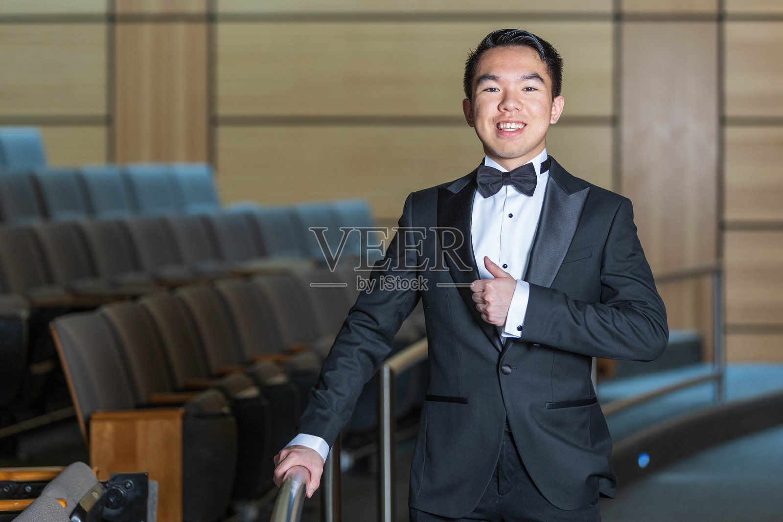 身穿礼服的年轻男子竖起大拇指。照片摄影图片