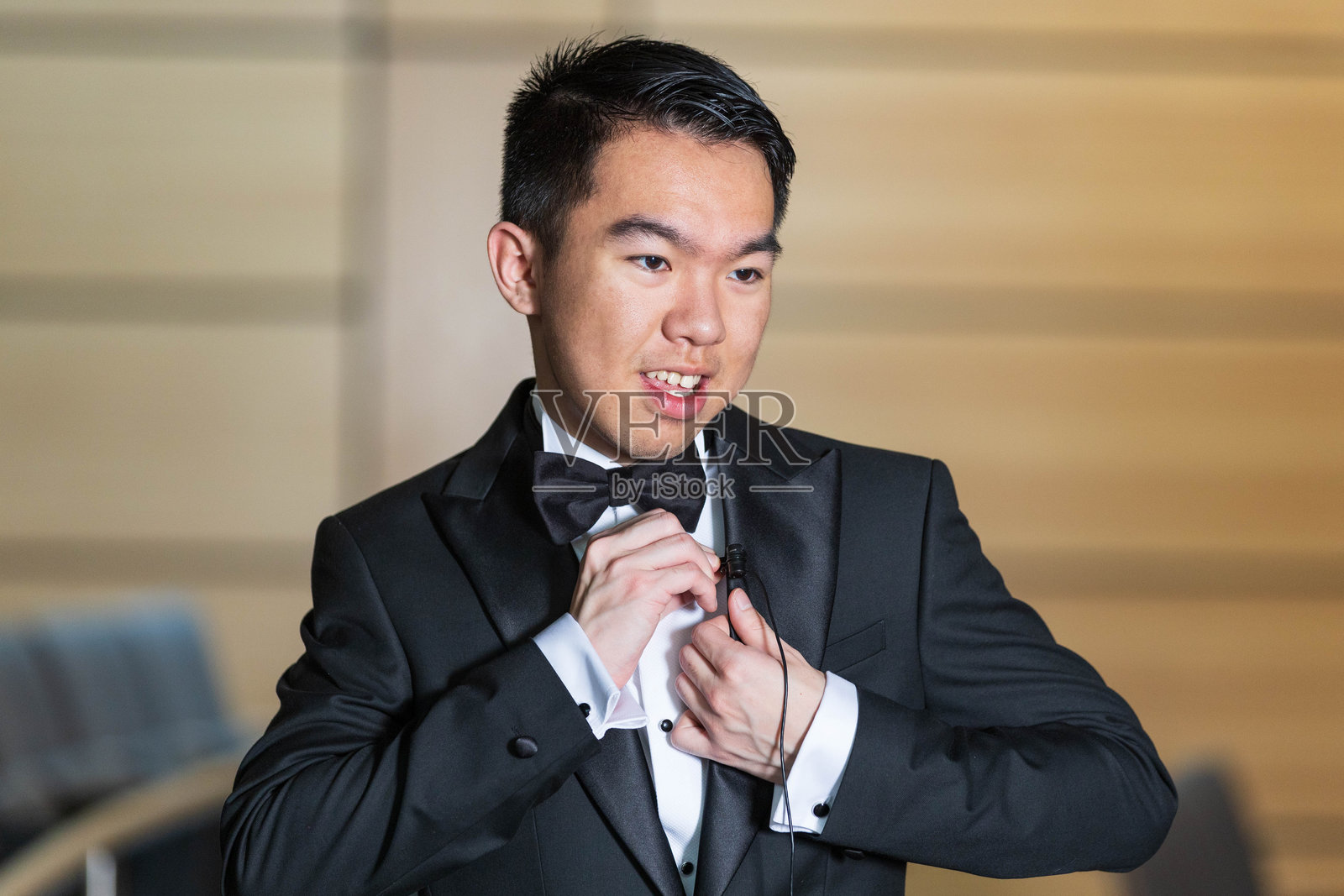 年轻男子穿着礼服，正在夹上领夹麦克风照片摄影图片