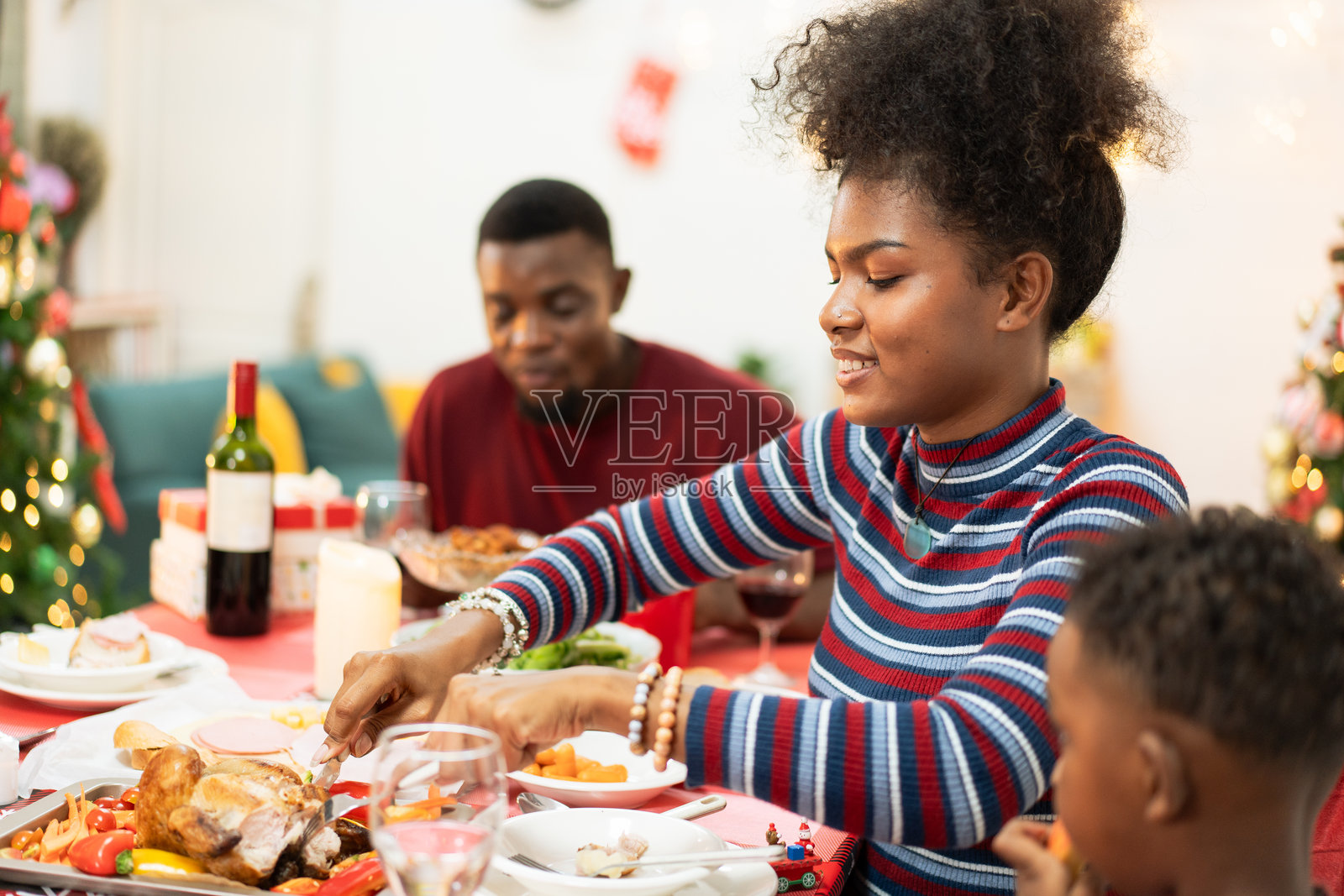 非洲家庭在家中共进圣诞晚餐。人们在餐桌上喝酒、吃饭，享受交谈的乐趣。节日庆祝派对，假期里有美味的盛宴。照片摄影图片