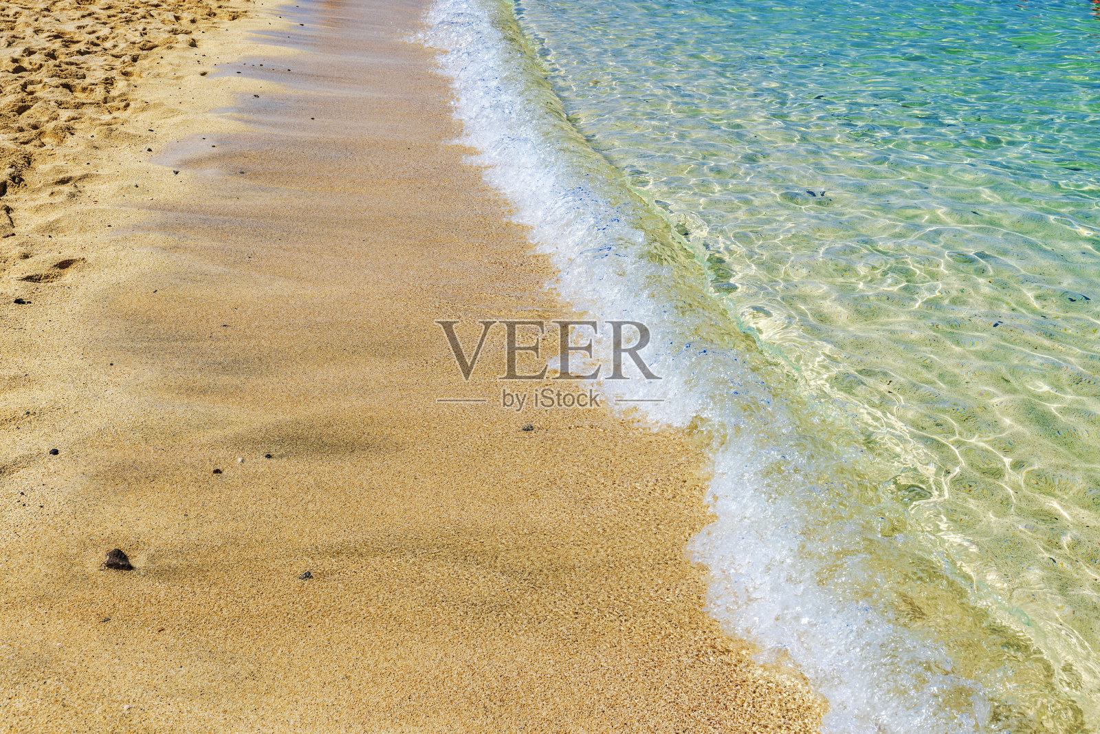 金色沙滩上，温柔的海浪拍打着岸边，在明亮的阳光下形成泡沫涟漪。西班牙照片摄影图片