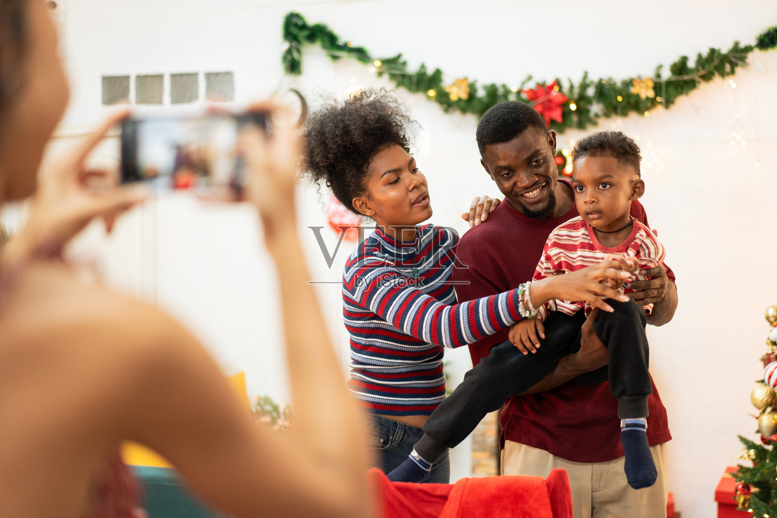 女人在节日庆祝派对上为非洲家庭拍照。快乐的人们一起享受新年的开始。照片摄影图片
