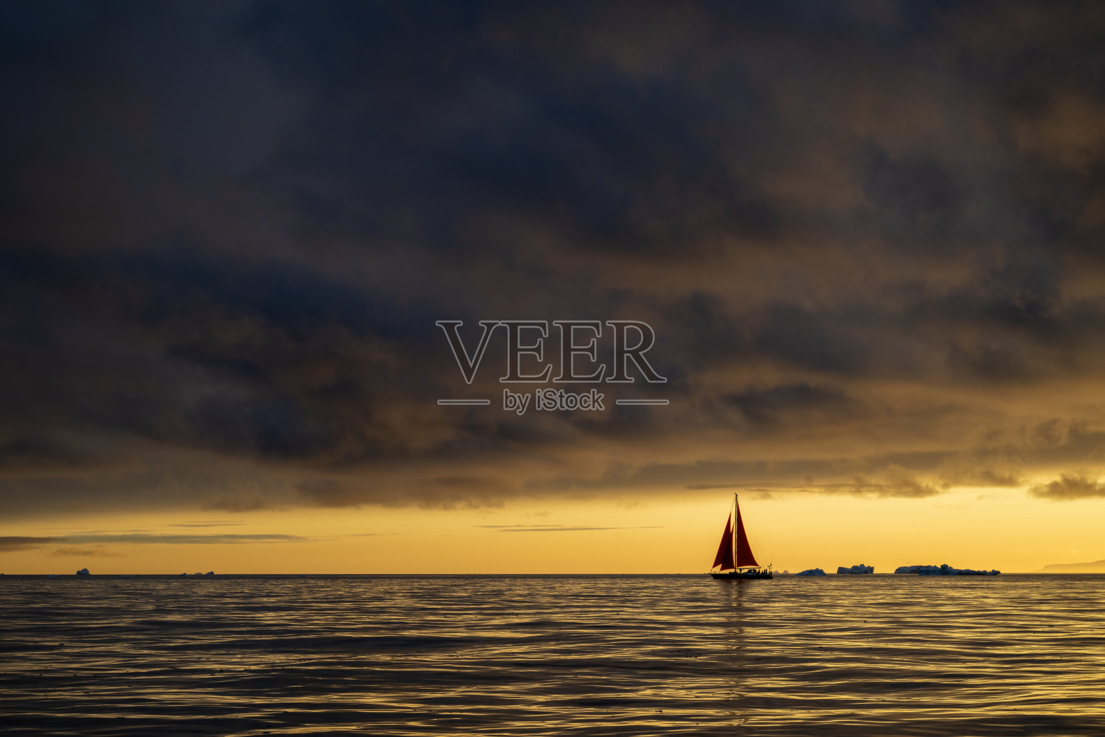 在格林兰伊卢利萨特的迪斯科湾，红色帆船在美妙的午夜日落中航行照片摄影图片