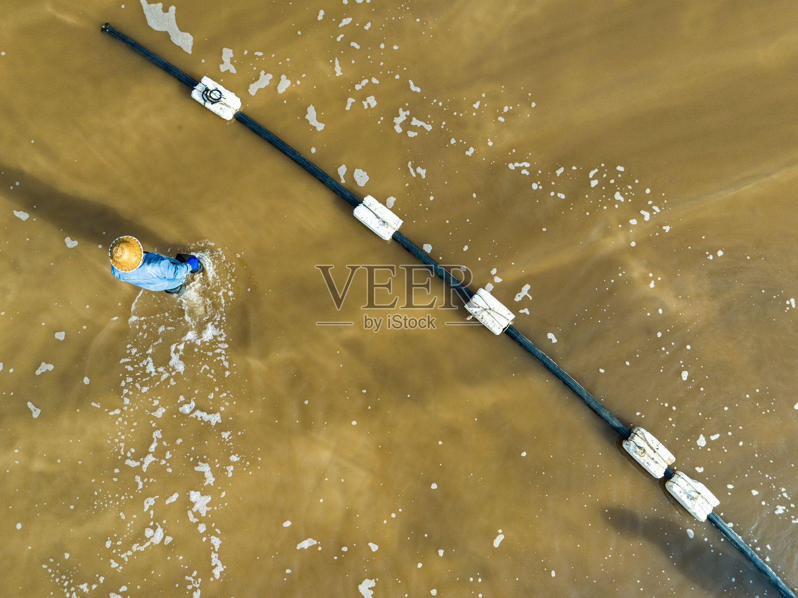 工人在盐田工作，盐场工人在盐田中生产盐。照片摄影图片