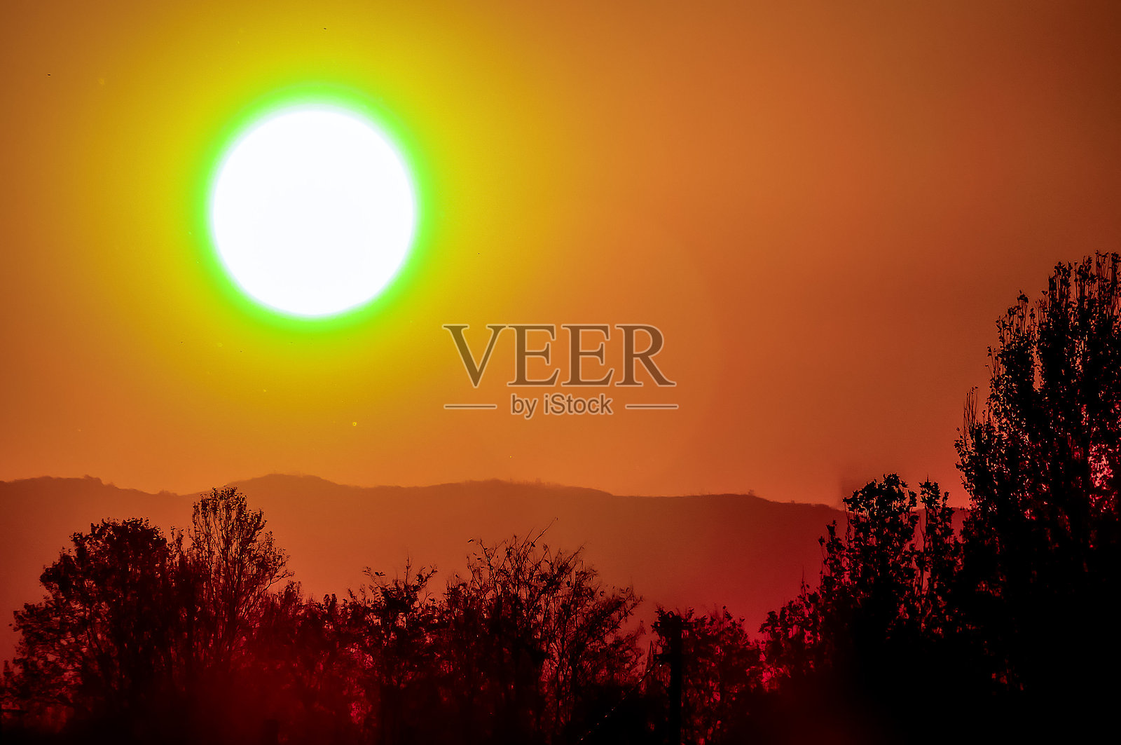 天空中有一个大型的黄色太阳，带有绿色的色调。照片摄影图片