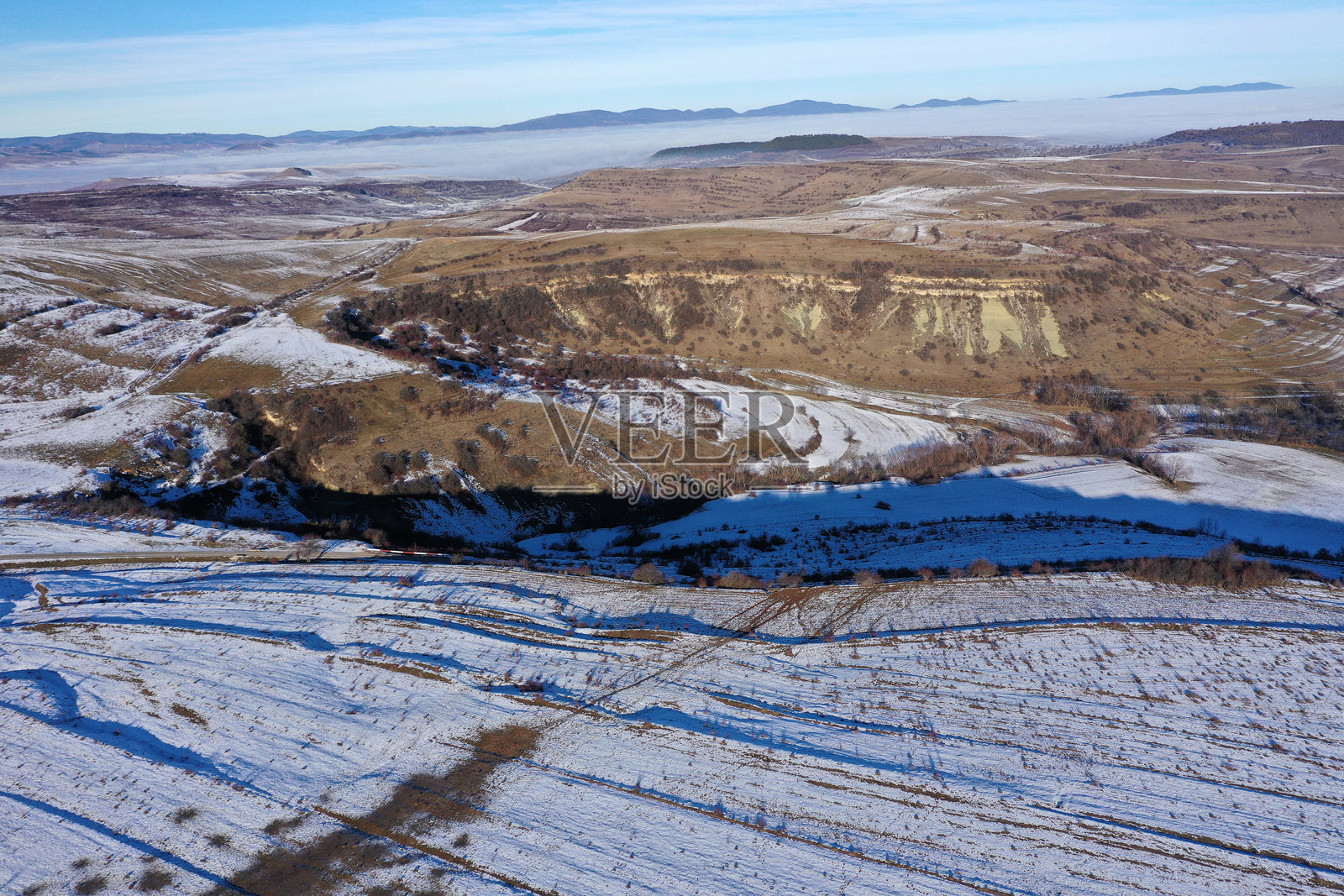 雾气弥漫的阳光明媚的日子，山丘上的融雪鸟瞰图照片摄影图片