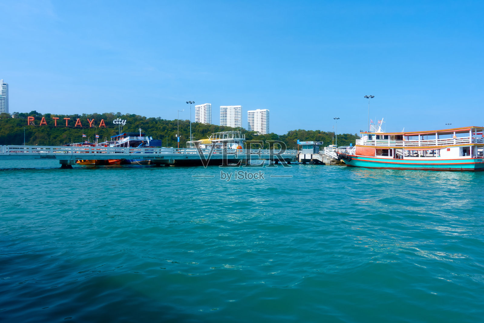 白天的芭堤雅湾和芭堤雅市景，快艇游船停靠在海湾中。照片摄影图片