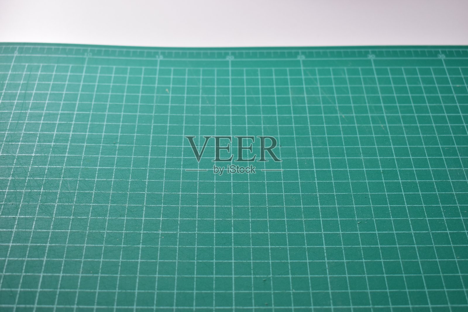 白色背景上的绿色切割垫，带有线条和刻度测量指南图案，适用于物体艺术设计和DIY手工工具设备。照片摄影图片