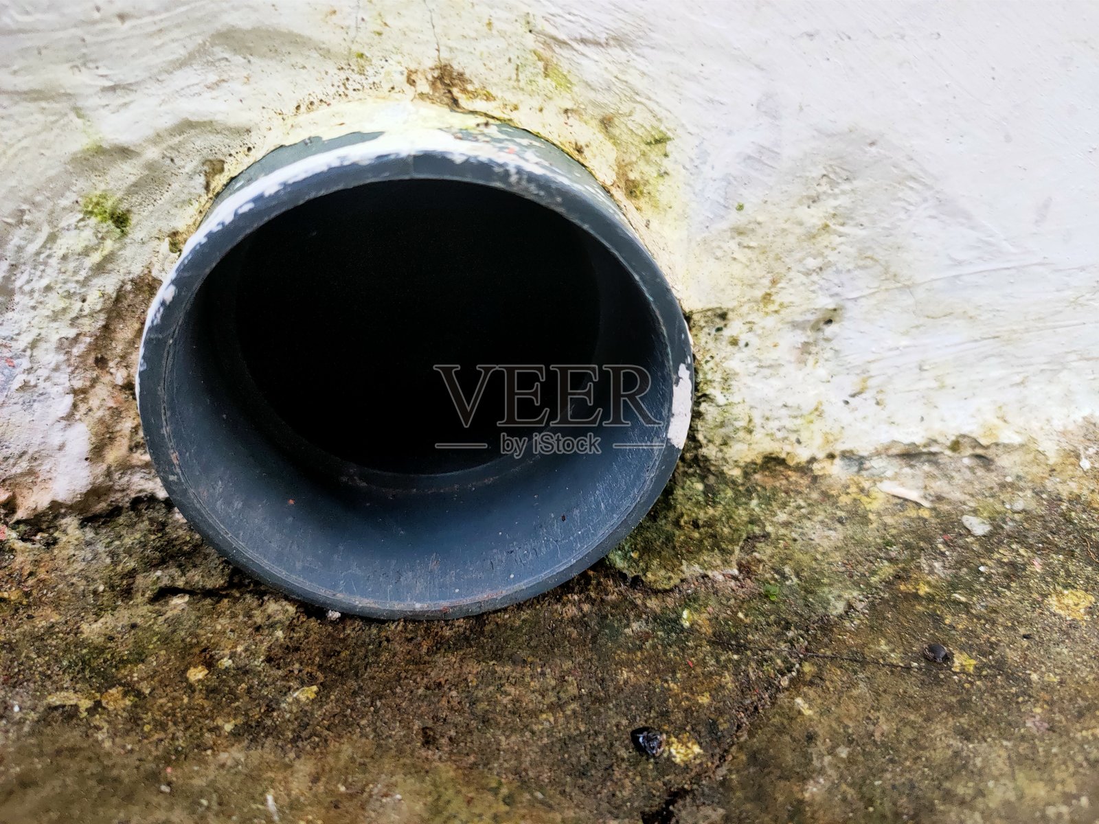 灰色排水管在肮脏的白色墙壁上。照片摄影图片