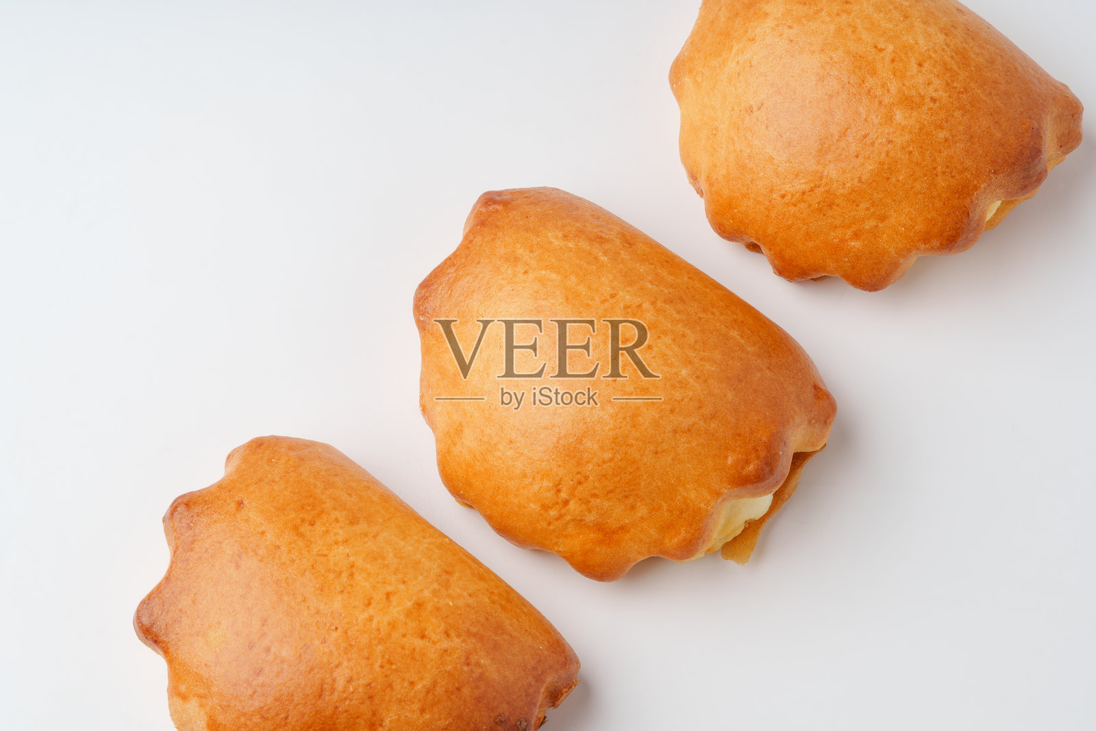 美味的烘焙点心整齐地摆放在厨房环境的浅色背景上，展示出它们的金黄色和质感。照片摄影图片