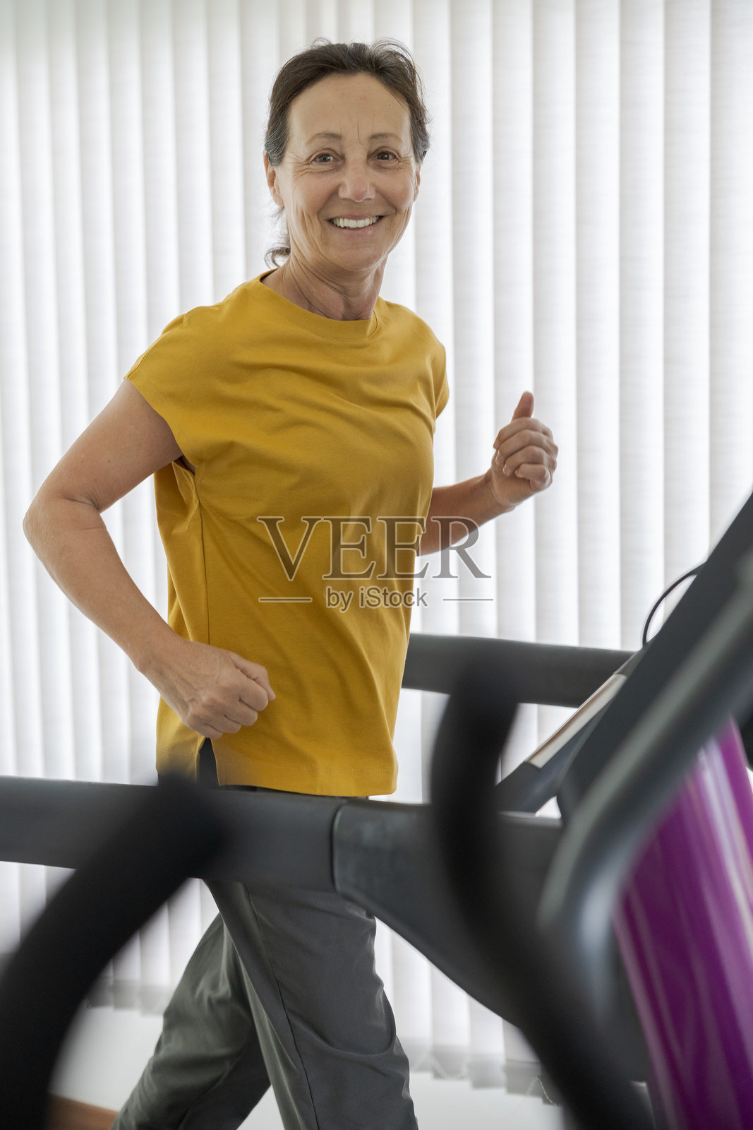 老年女性在健身中心跑步机上锻炼照片摄影图片