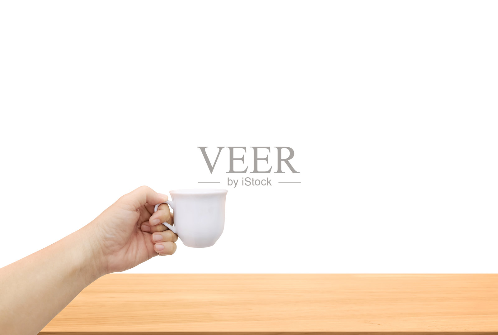一只手握着白色陶瓷咖啡杯，放在木桌上，背景为白色。照片摄影图片