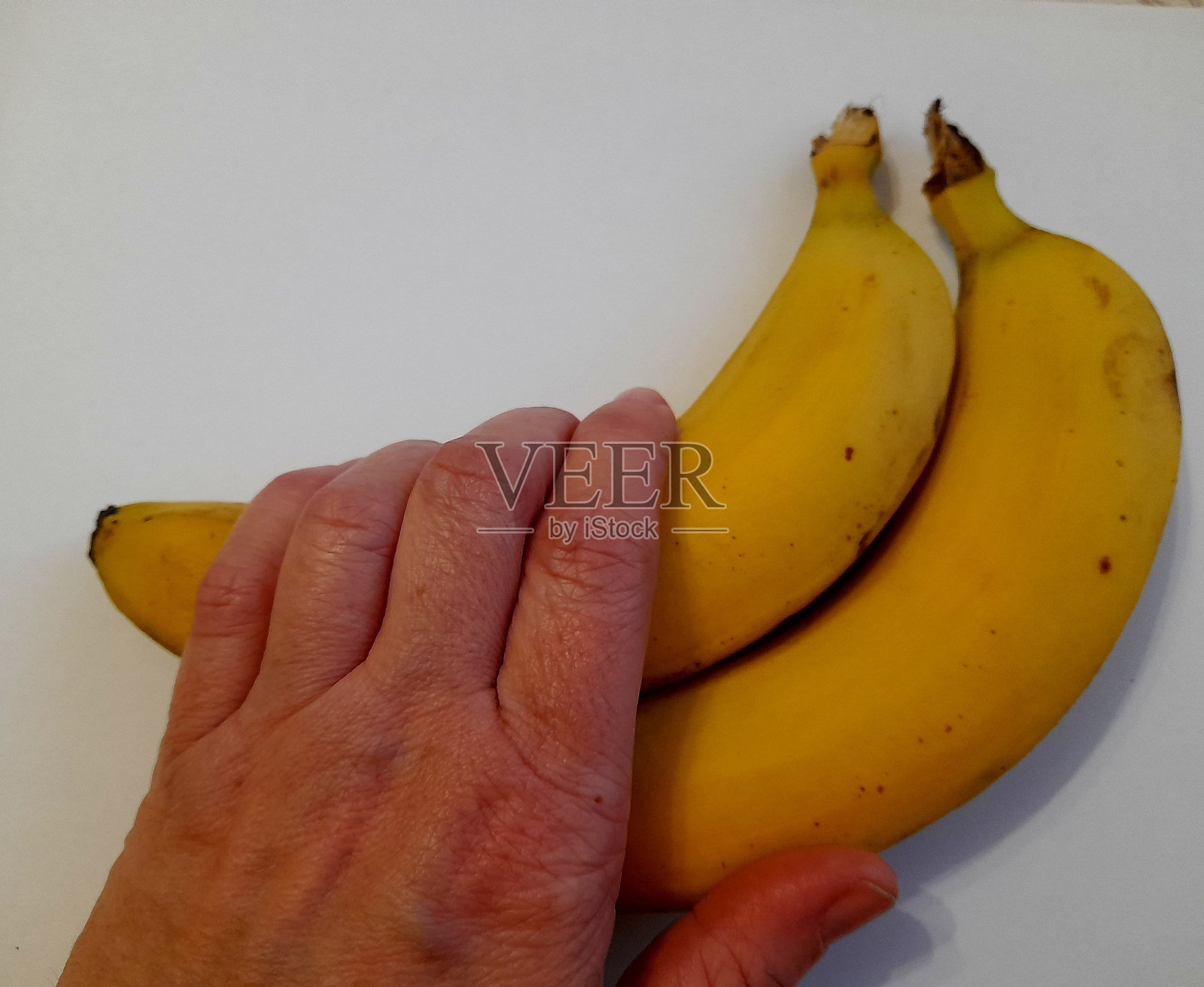 手握香蕉，背景为白色照片摄影图片