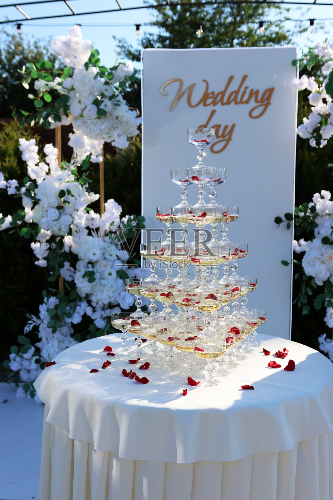 美丽的香槟杯金字塔，上面撒满玫瑰花瓣和冰块。节日接待。照片摄影图片