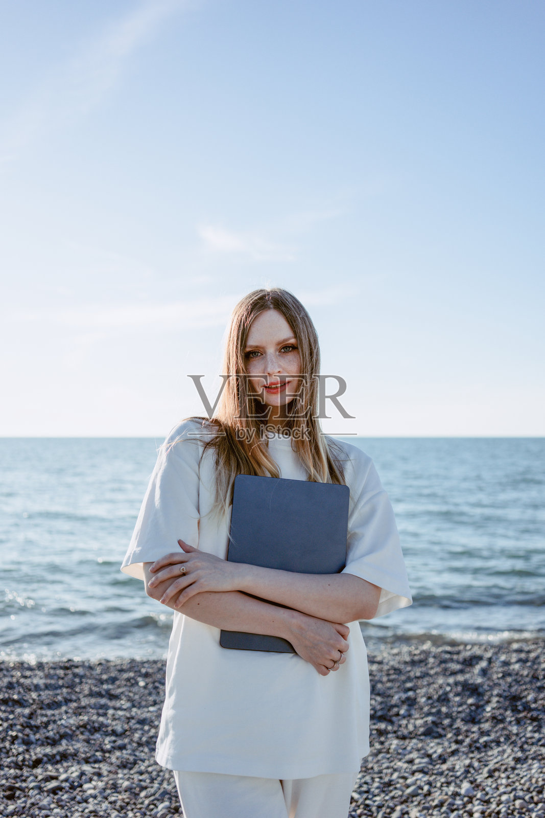 一个女孩在海滩上用笔记本电脑工作。自由职业程序员。房地产经纪人。高质量照片照片摄影图片