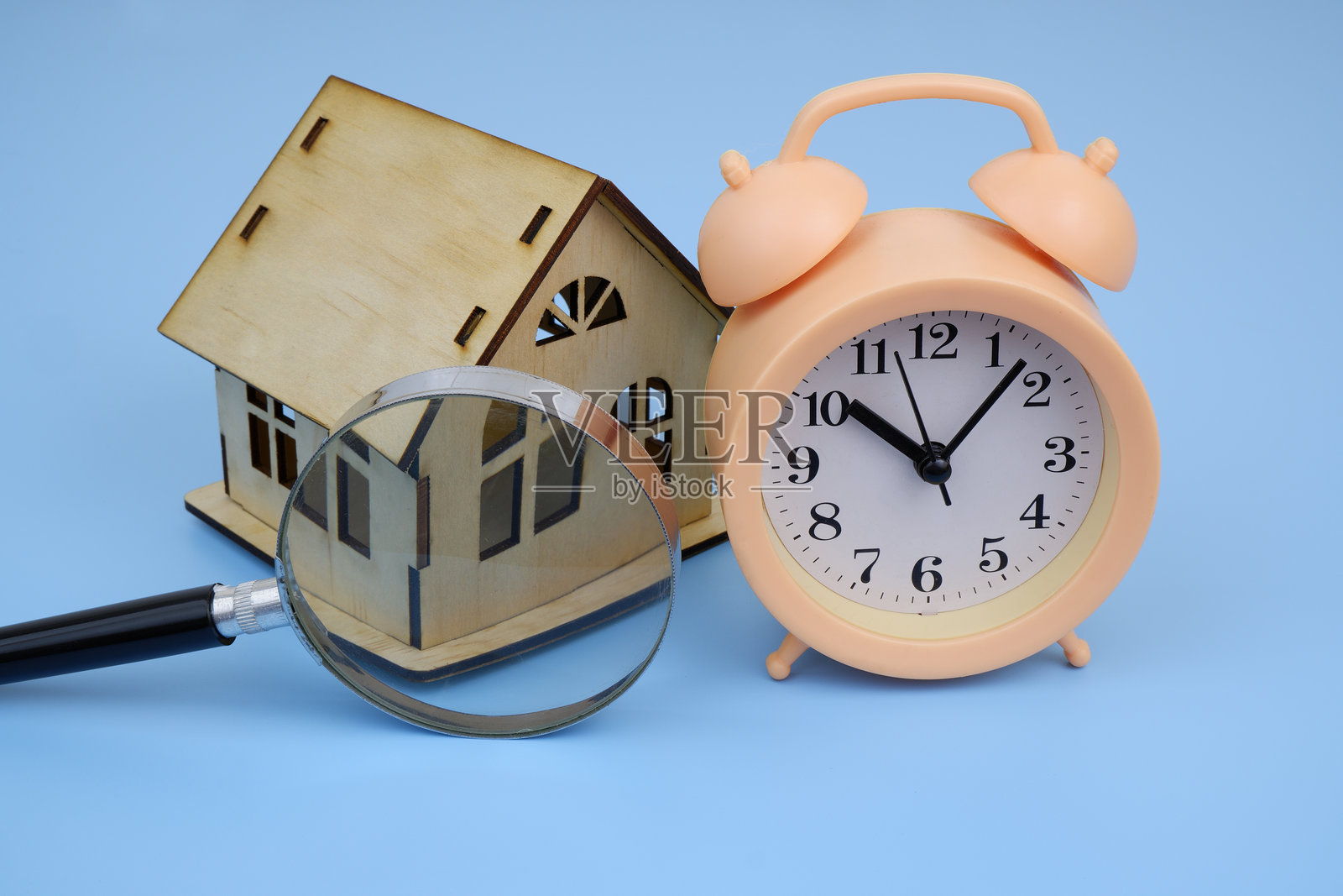 放大镜下的木屋模型和闹钟照片摄影图片