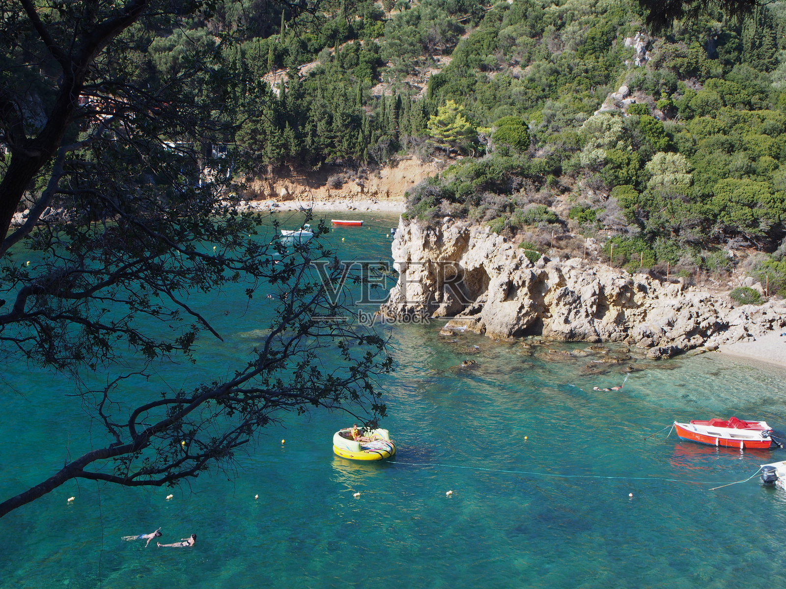 从上方俯瞰希腊科孚岛（克基拉）一个小海湾，游泳的人们在水中尽情享受。照片摄影图片