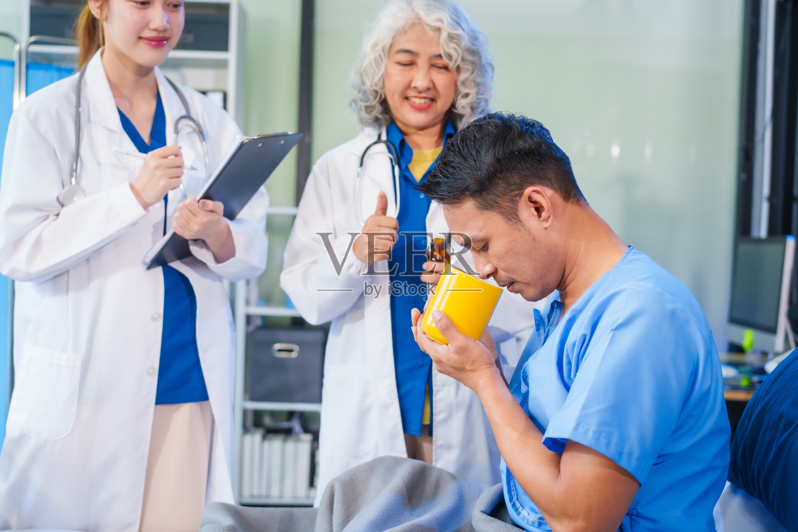 两名女医生在医院病床上检查一名患者，讨论病历，给予药物，并提供鼓励，确保关怀的护理并促进患者的康复。照片摄影图片