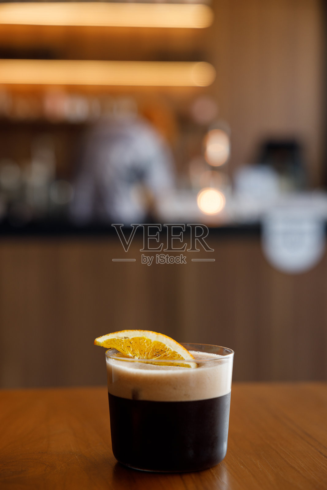 装饰有橙子的创意咖啡无酒精鸡尾酒杯放在木桌上。照片摄影图片