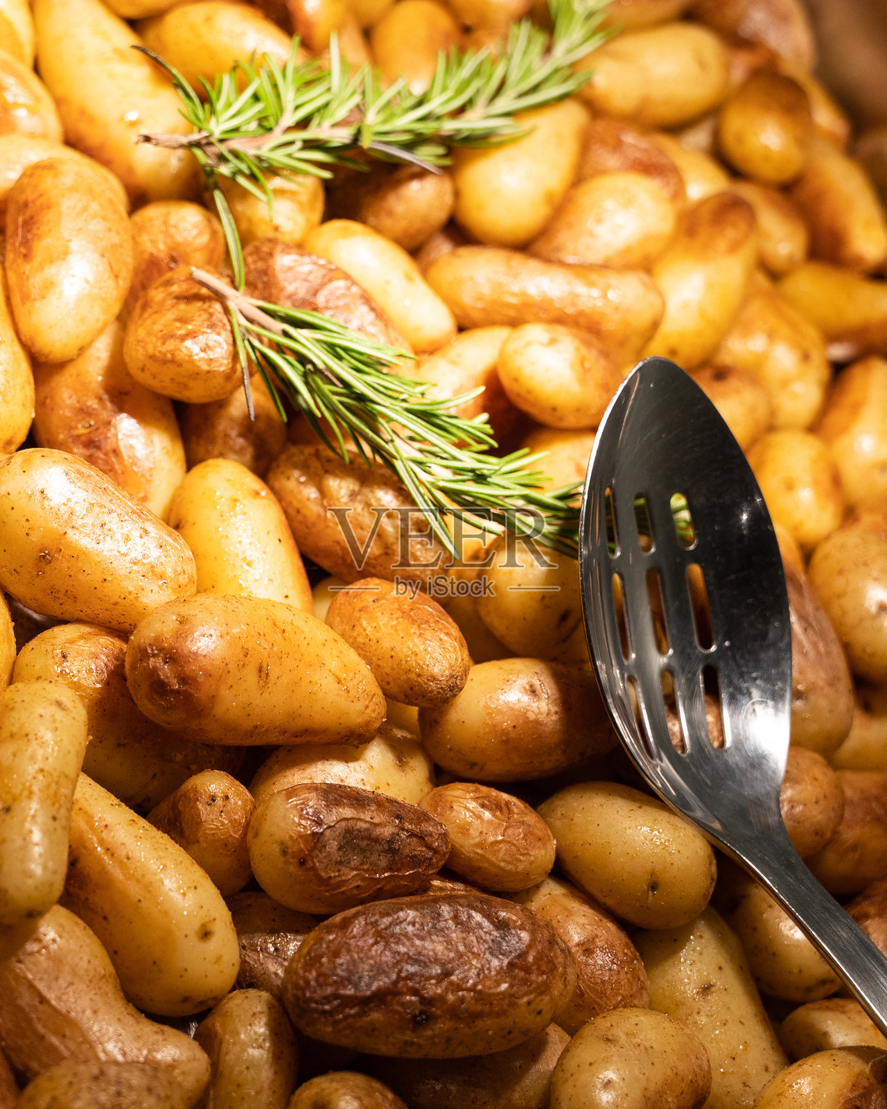 整颗土豆在烤箱中烤制，配有一枝迷迭香照片摄影图片