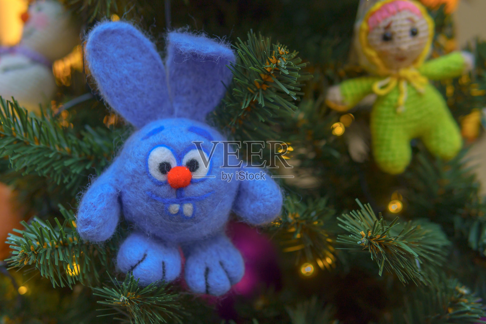 蓝色兔子圣诞玩具挂在圣诞树的枝条上。照片摄影图片