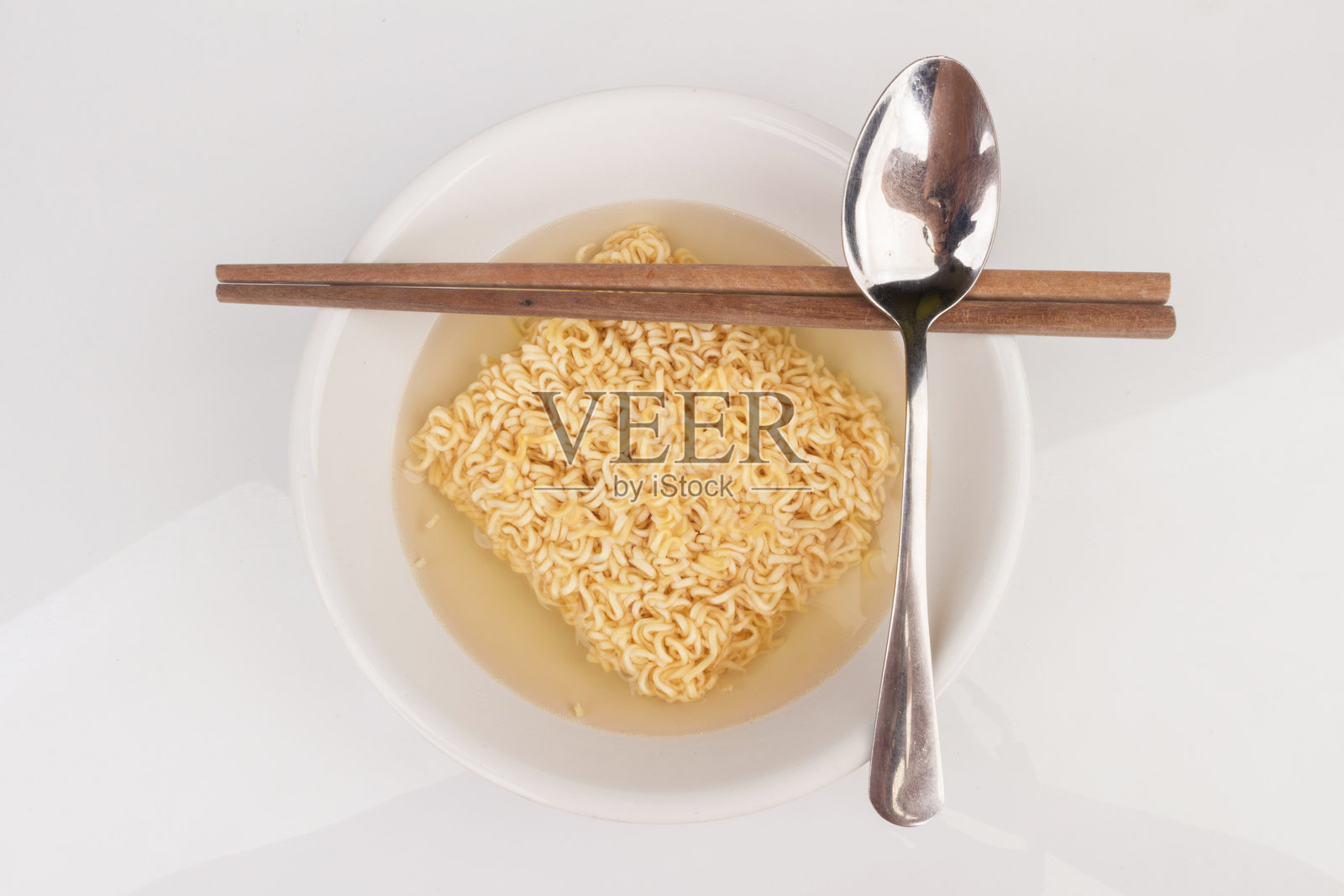 白色背景上盘子里的方便面和筷子勺子孤立摆放照片摄影图片