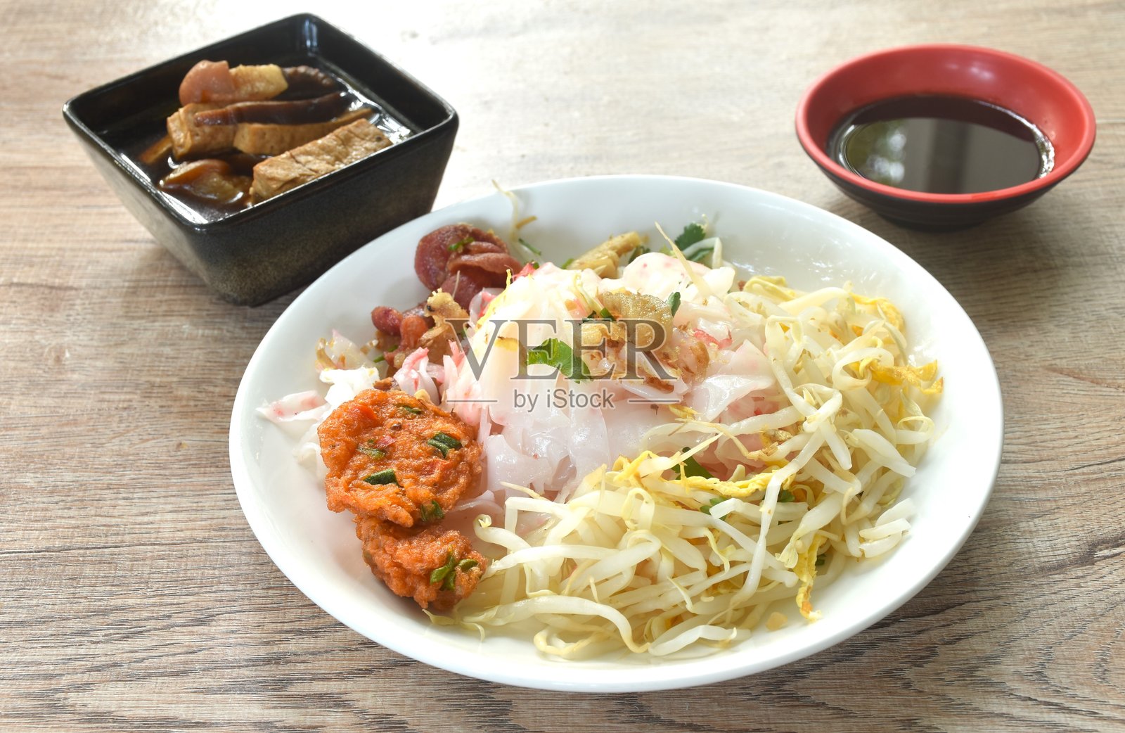 蒸大米粉，上面放有切片的炸中国香肠和脆皮猪肉，配以豆芽、黑酱油和酸豆瓣酱的调味。照片摄影图片