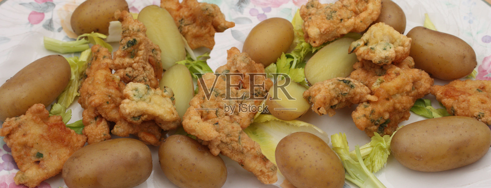 裹面包屑的咸鳕鱼饼，配以煮土豆和绿色沙拉照片摄影图片