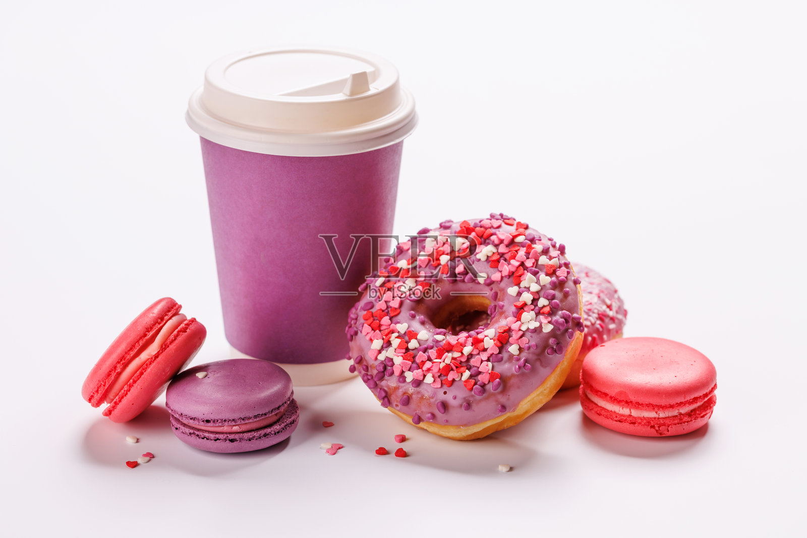 色彩缤纷的马卡龙、甜甜圈和纸杯咖啡在白色背景上的欢快展示照片摄影图片