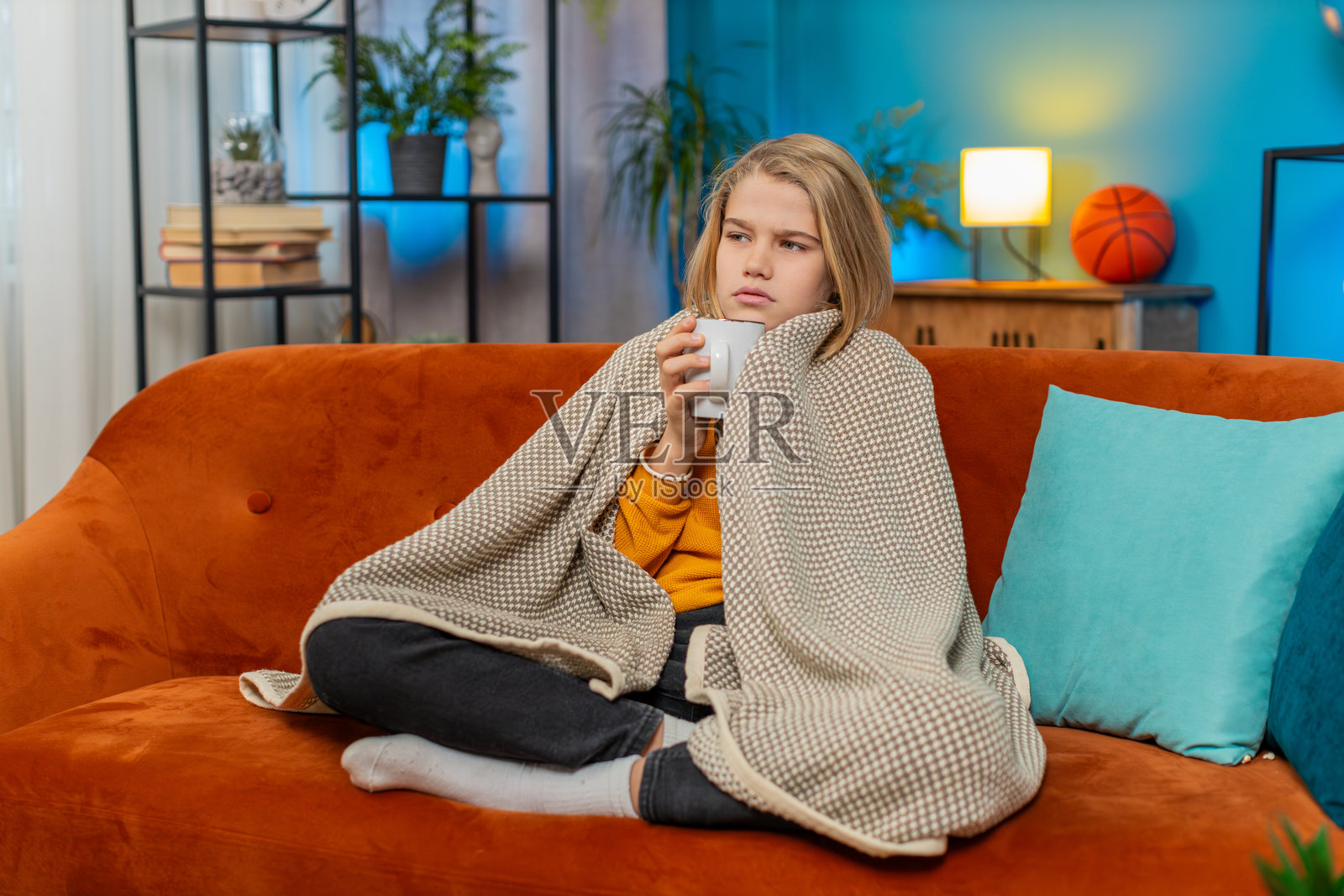 生病的少年男孩感冒和过敏，裹着毯子，喝着温暖的茶，在家咳嗽。照片摄影图片